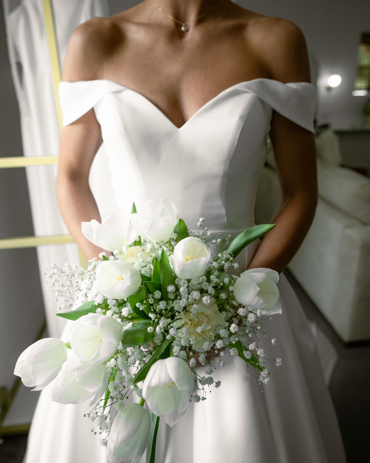 Elegant white bridal bouquet with baby's breath and tulips against a wedding dress.