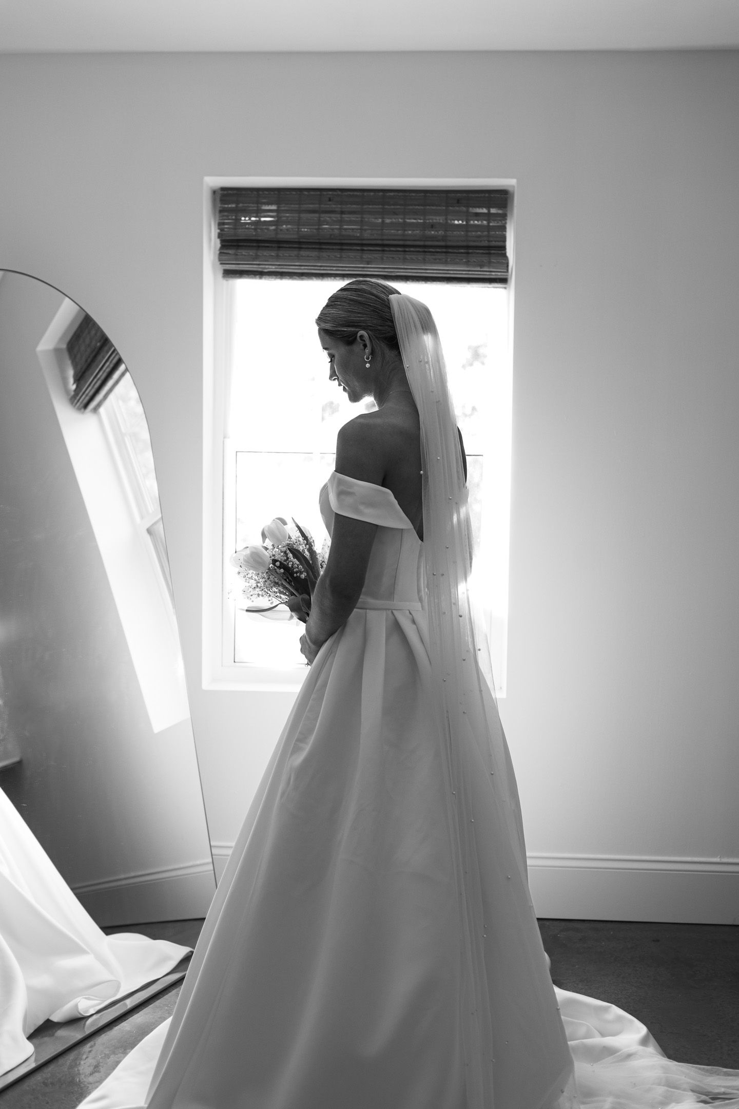 Silhouette of a wedding dress in a bright window, shown in black and white.