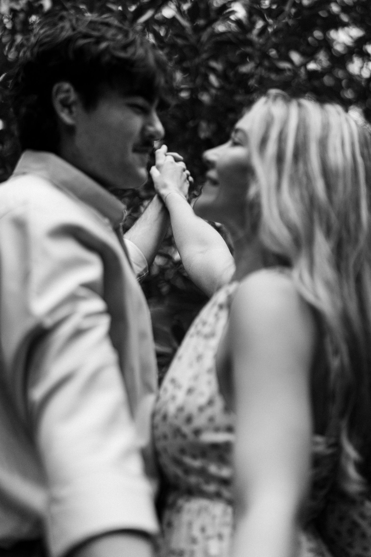 An intimate black and white moment between a couple sharing a tender moment outdoors.