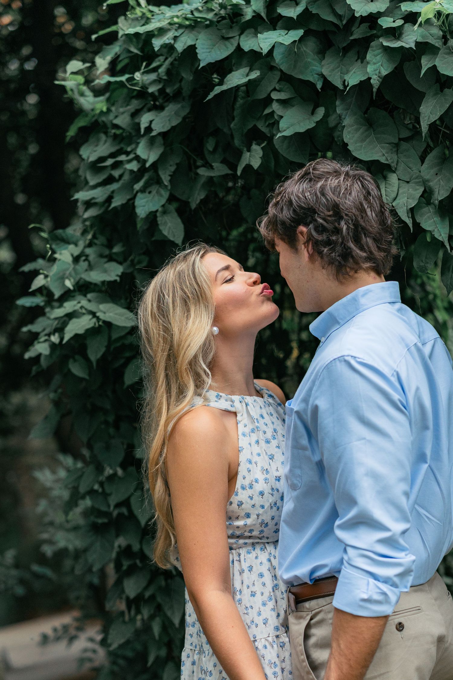 An intimate moment captured between a couple surrounded by lush green leaves.
