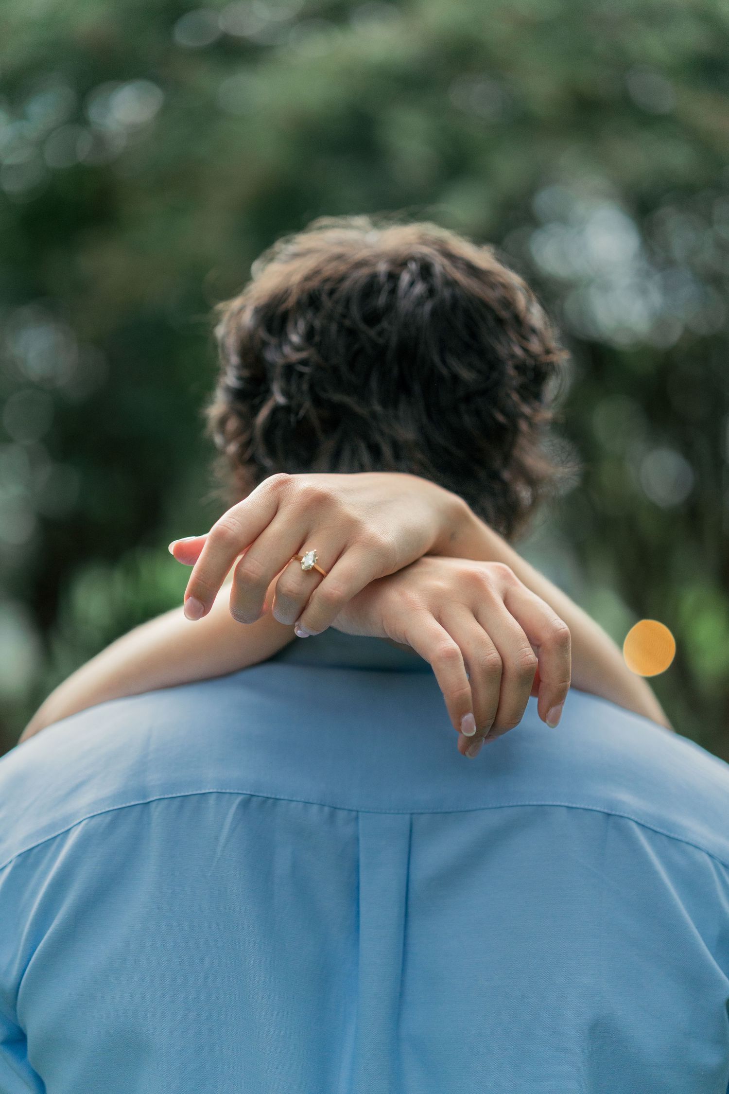 Close-up view of hands resting on a light blue button-down shirt.
