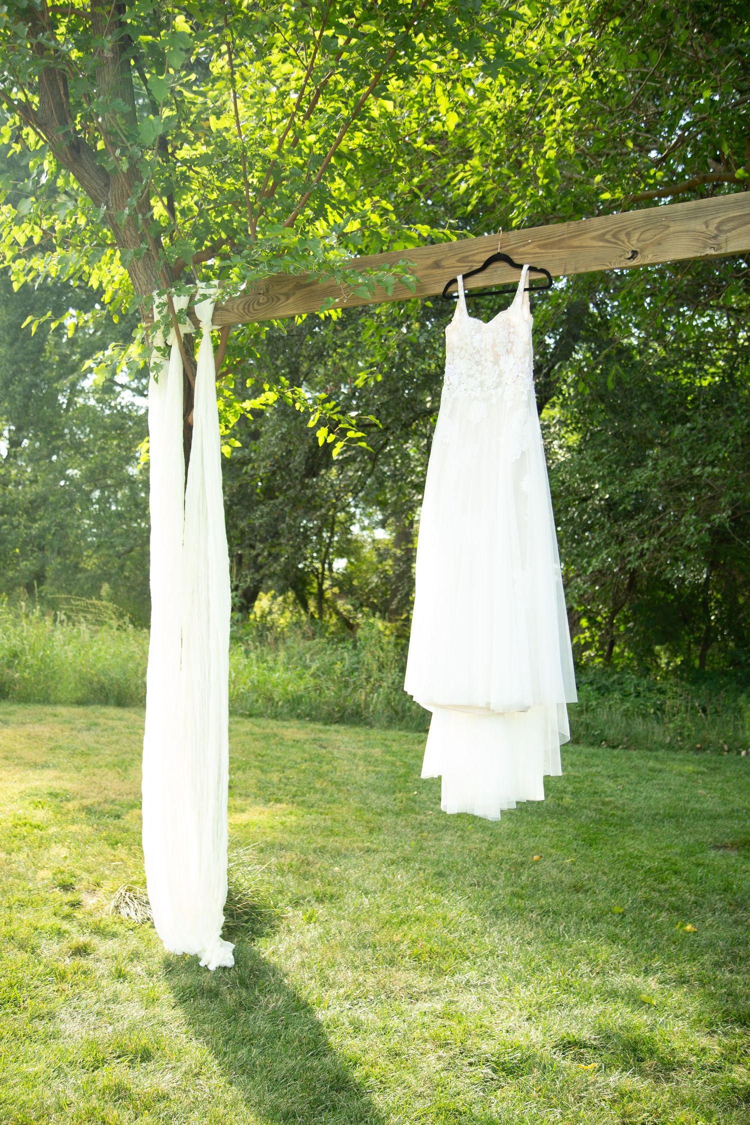 Elegant wedding dress hanging from a picturesque archway, capturing the beauty and anticipation of a perfectly planned wedding day.