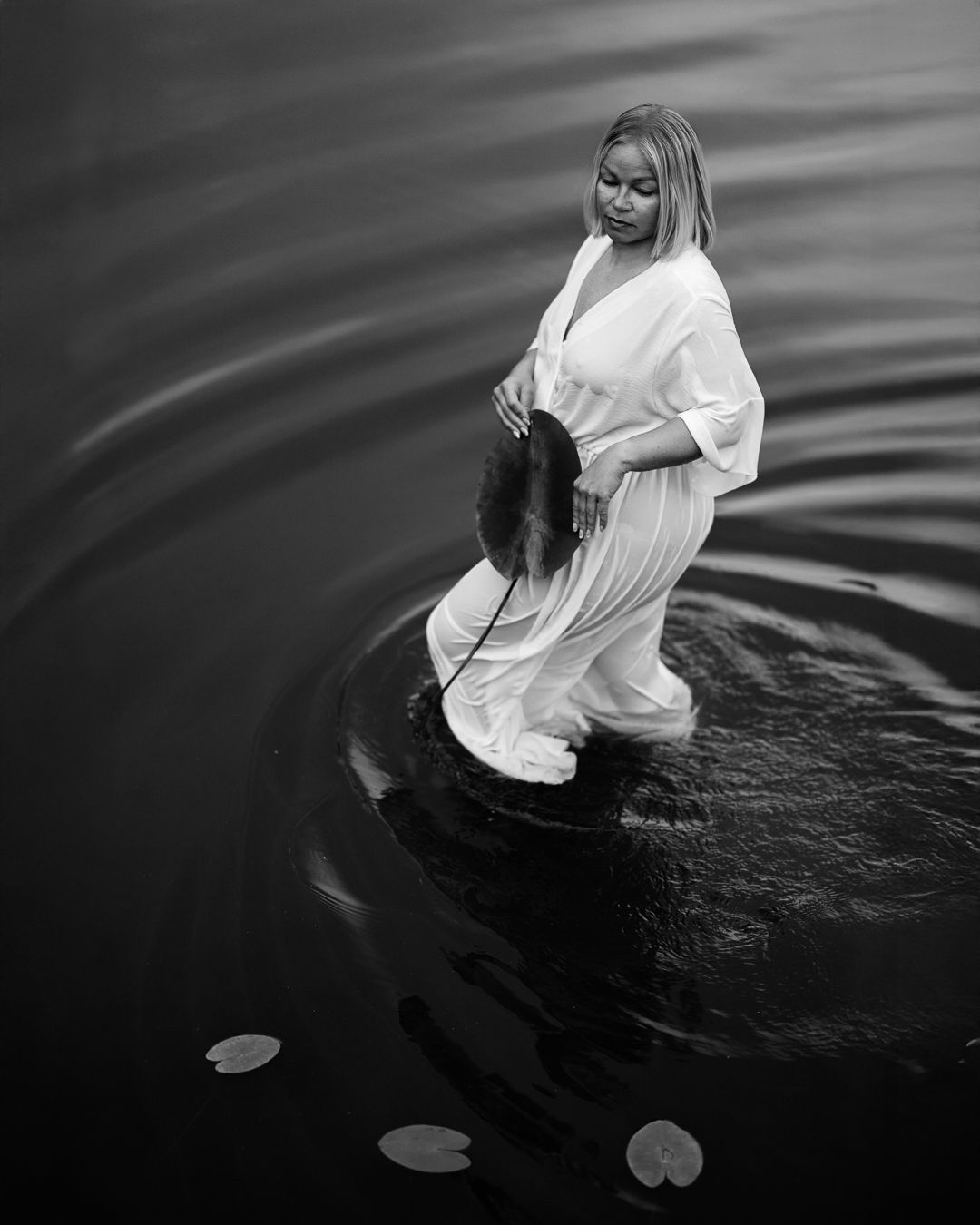 Black and white portrait of a woman in a white shirt wading in rippled open water
