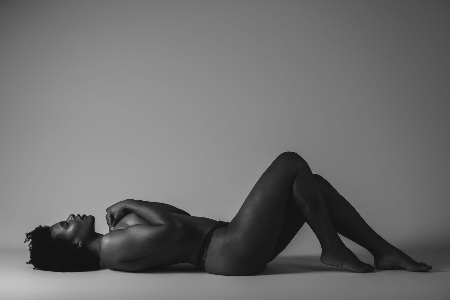 Black and white boudoir photo of a woman lying on the floor, Brussels studio