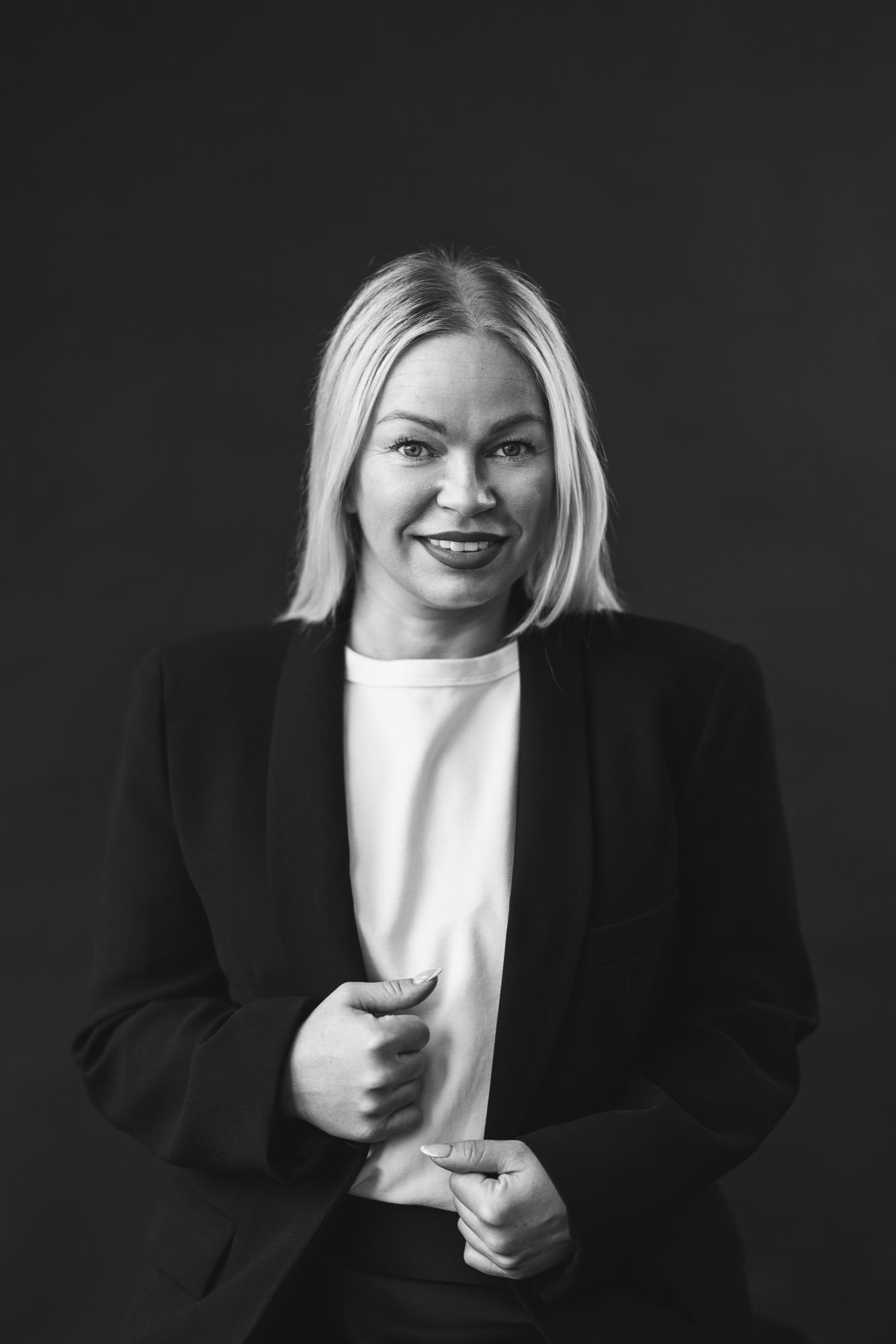 Black and white headshot of a woman in a dark blazer against a plain studio background