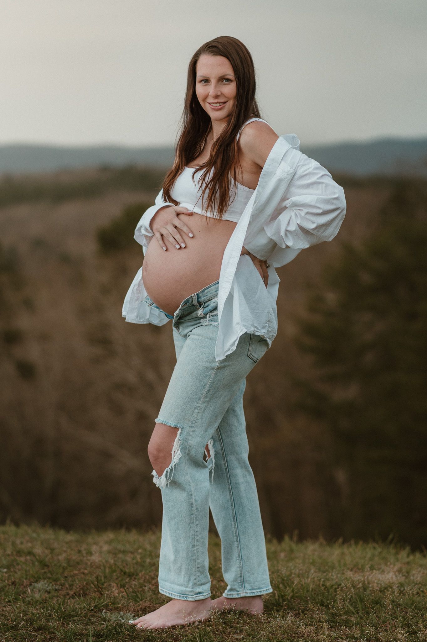 Profile portrait of expecting mom holding bump looking at camera during maternity session on raccoon mountain chattanooga tn, overlook