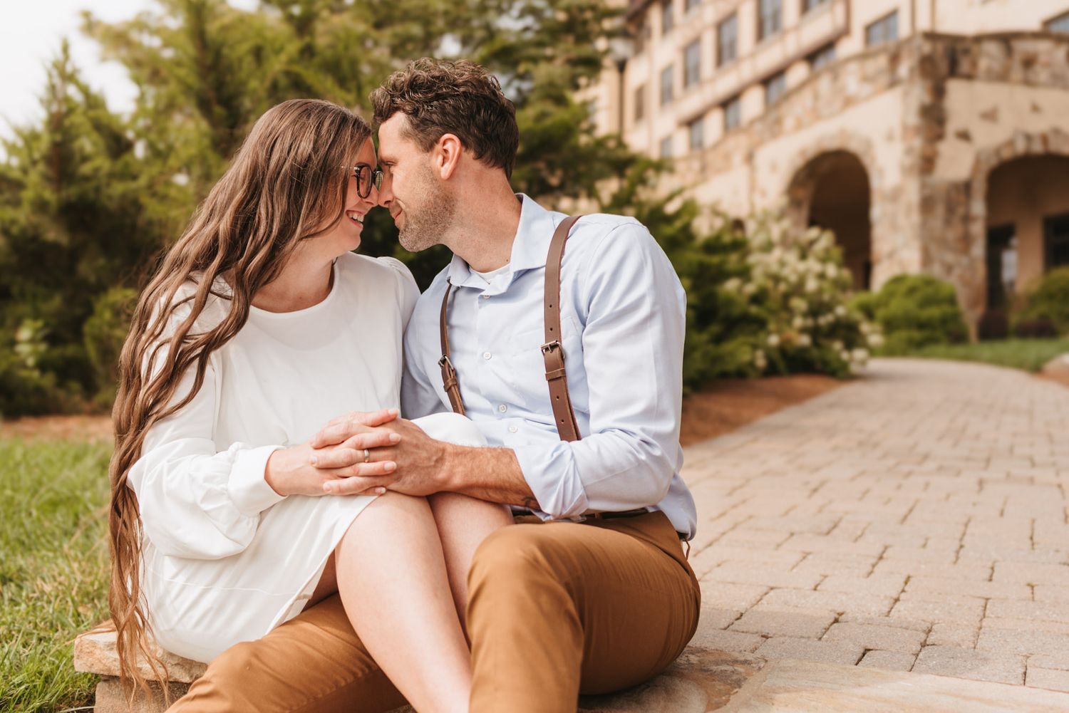 Intimate moment between couple sitting close head to head on pathway, outdoor morning session on lookout mountain Georgia, architecture