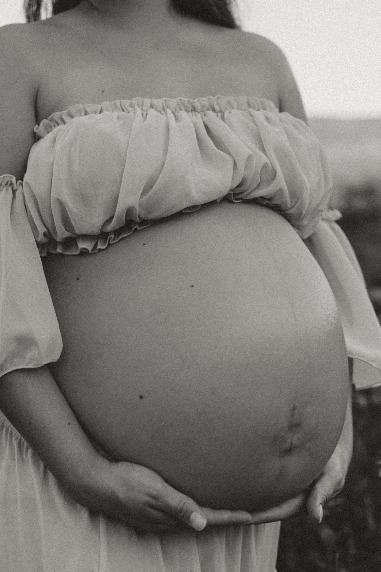 Black & white close up of expectant moms bump in a wildflower field during maternity session at Fox Mountain Farm in Rising Fawn, Georgia
