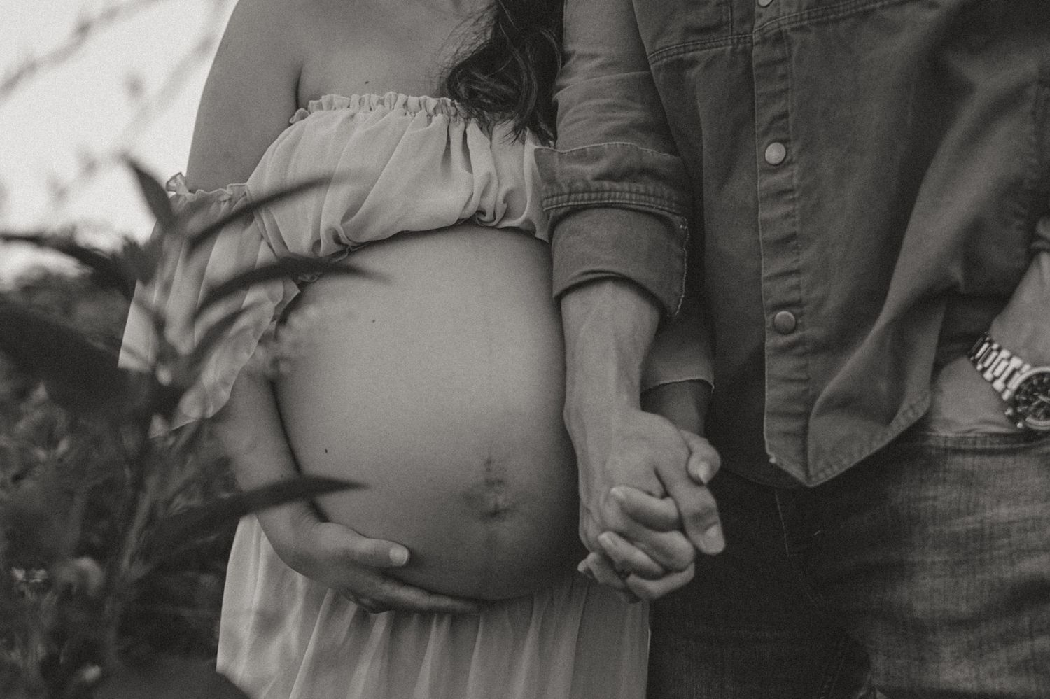 Close up black & white of expecting couple holding hands in field during maternity session at Fox Mountain Farm in Rising Fawn, Georgia