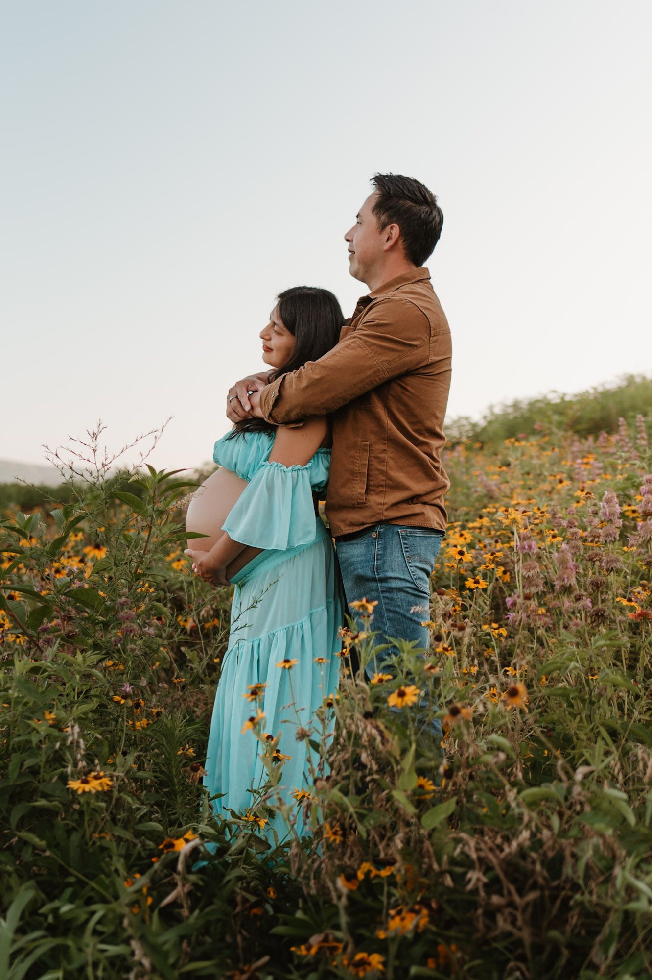 Expecting couple standing in a wildflower field during golden hour maternity session at Fox Mountain Farm in Rising Fawn, Georgia