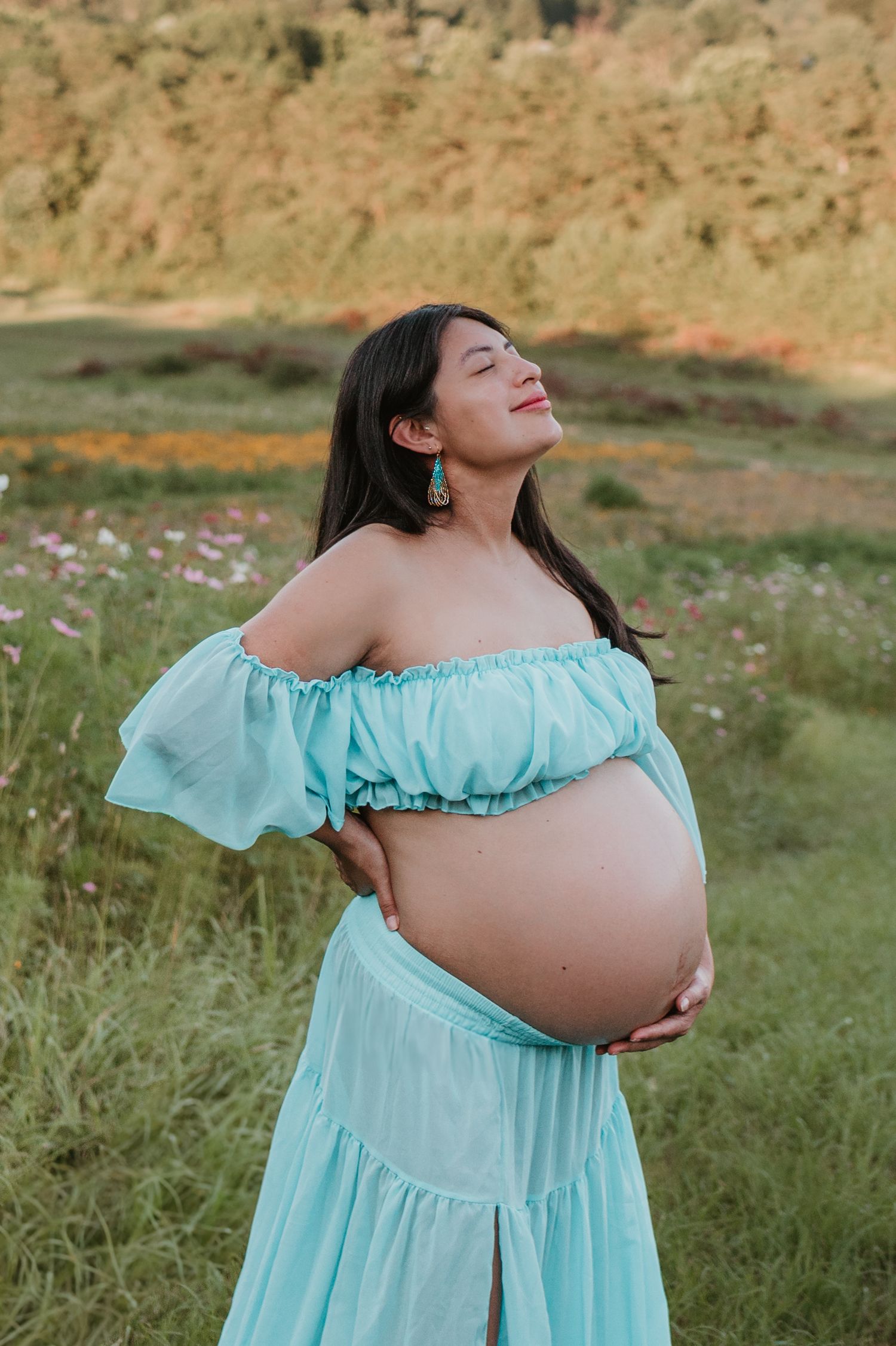 Itzayana holding belly looking up in a wildflower field at Fox Mountain Farms, Chattanooga, TN – maternity session, soft summer light