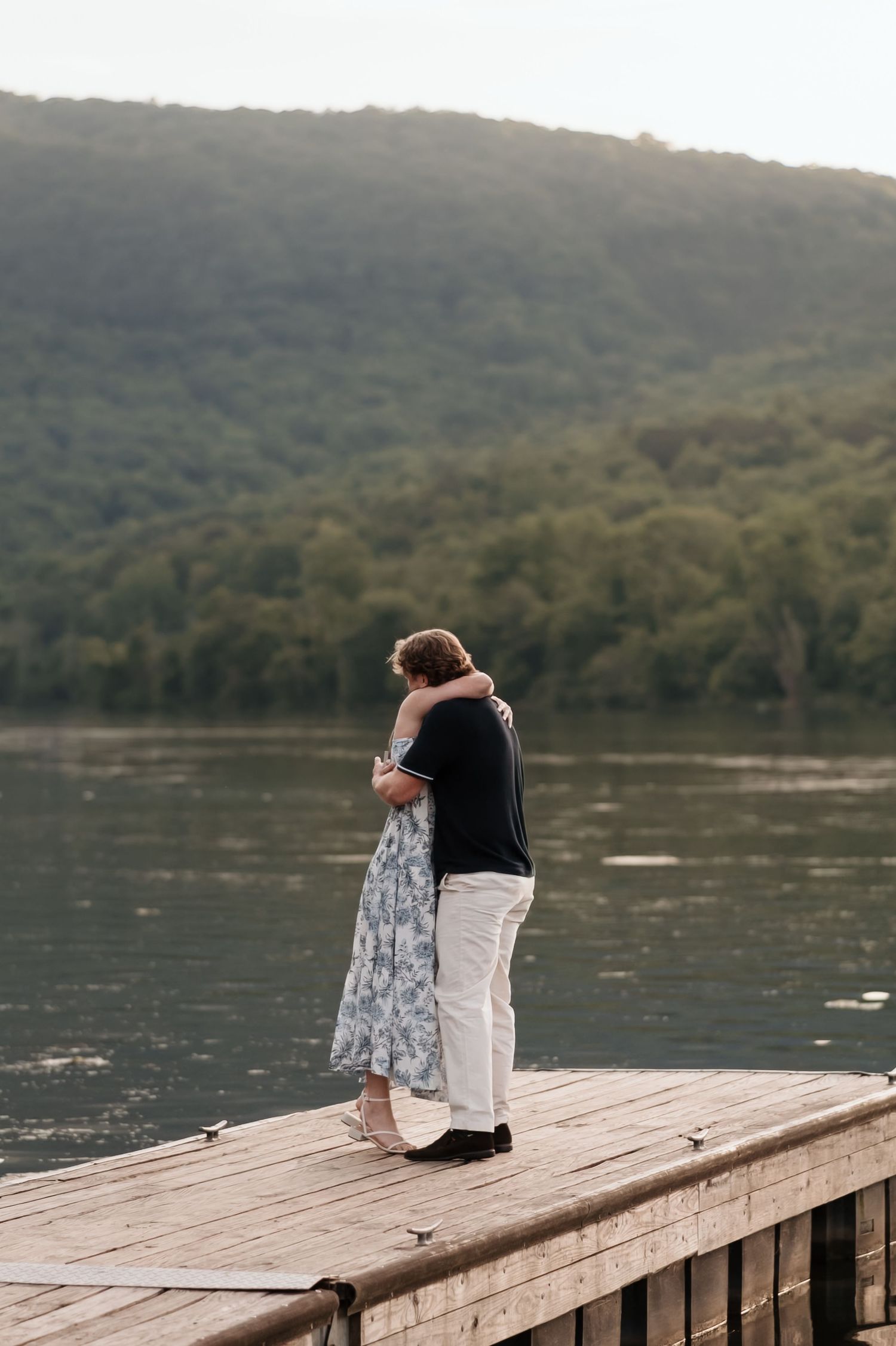 Couple hugs after surprise proposal near river and raccoon mountain during couples engagement session