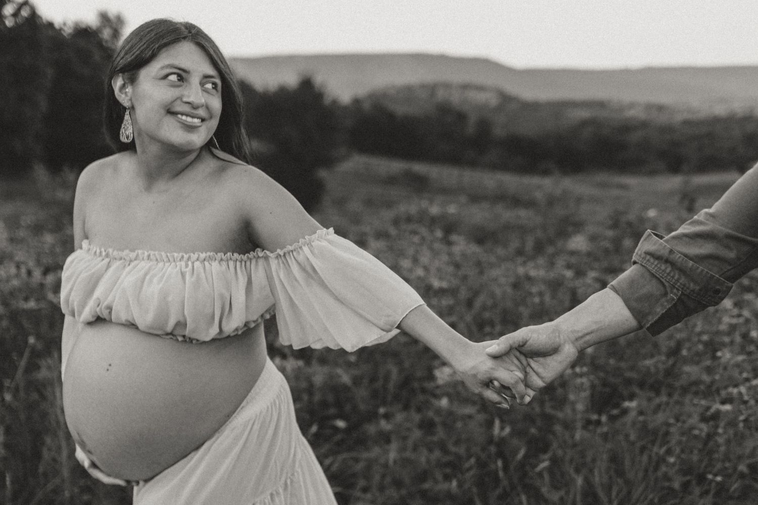 Itzayana walking and looking back in a wildflower field at Fox Mountain Farms, Chattanooga, TN – maternity session, soft summer light