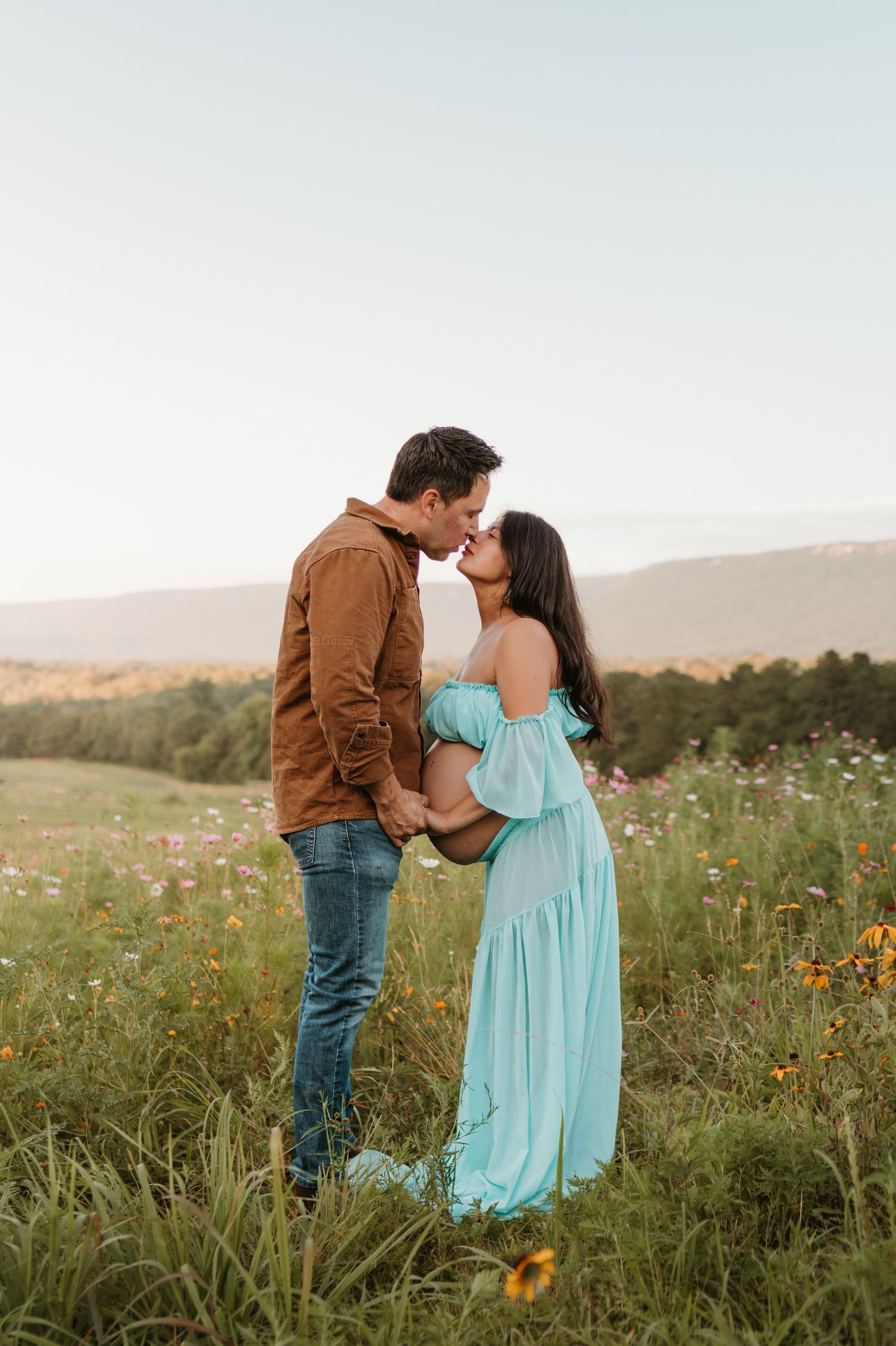 Couple kissing in a wildflower field at Fox Mountain Farms, Chattanooga, TN – maternity session, soft summer light