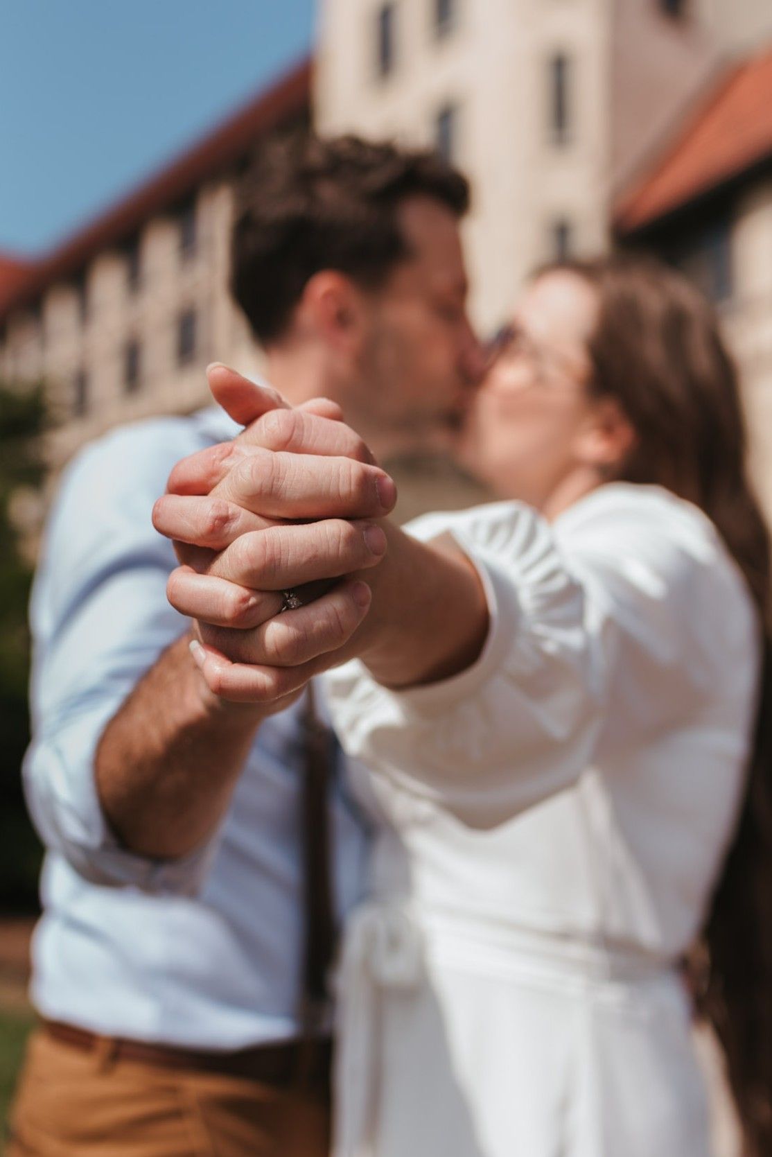 close up of couple holding hands with them kissing in background, morning light session on lookout mountain, georgia