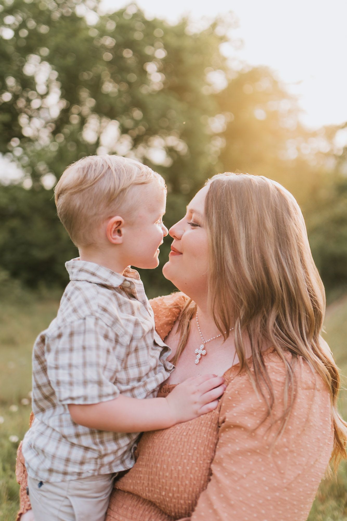 Expecting mom holding toddler close nose to nose in field during family maternity session at raccoon mountain, Chattanooga TN, golden hour