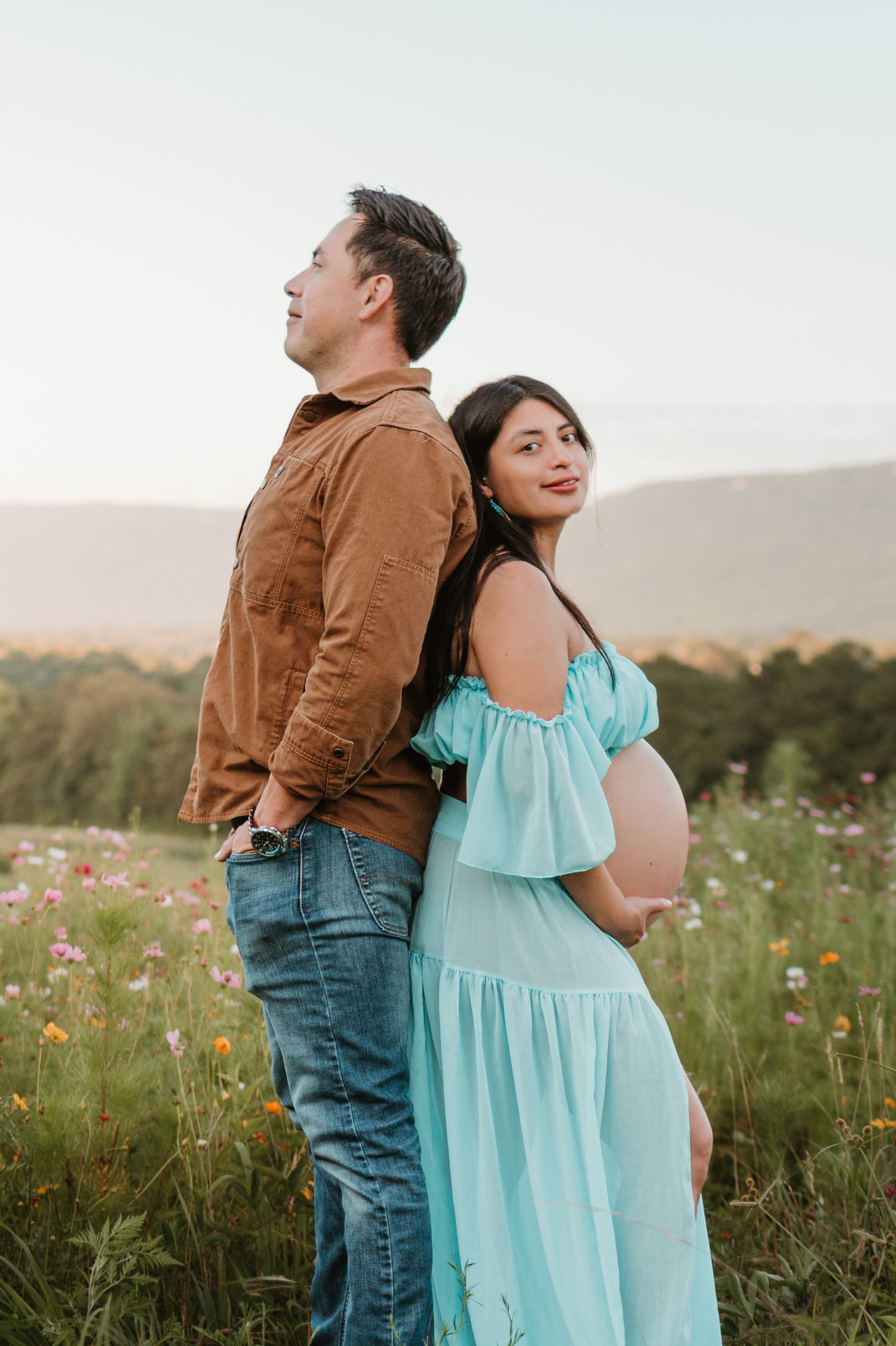 Couple back to back in a wildflower field at Fox Mountain Farms, Chattanooga, TN – maternity session, soft summer light