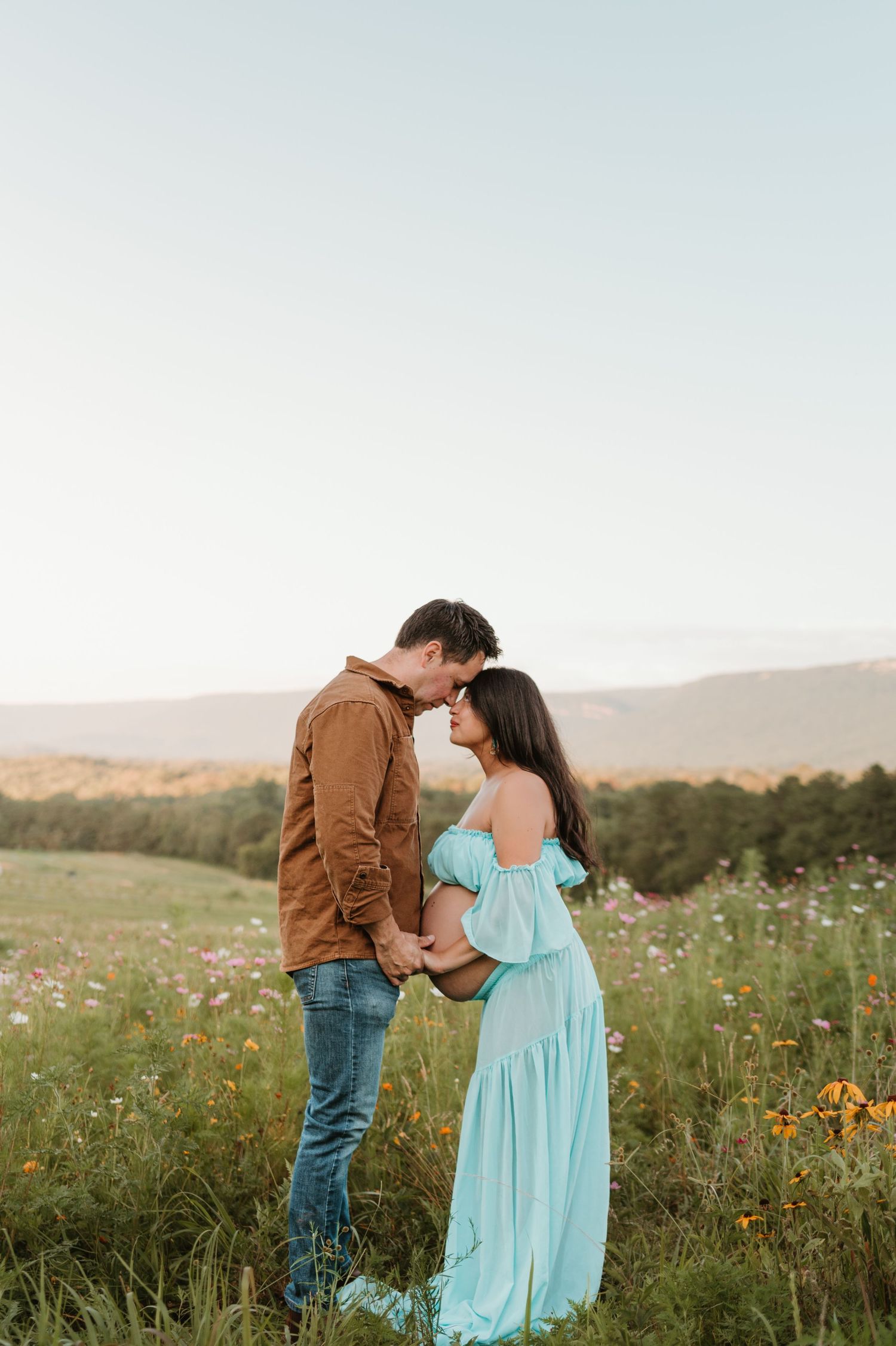Couple forehead to forehead in a wildflower field at Fox Mountain Farms, Chattanooga, TN – maternity session, soft summer light