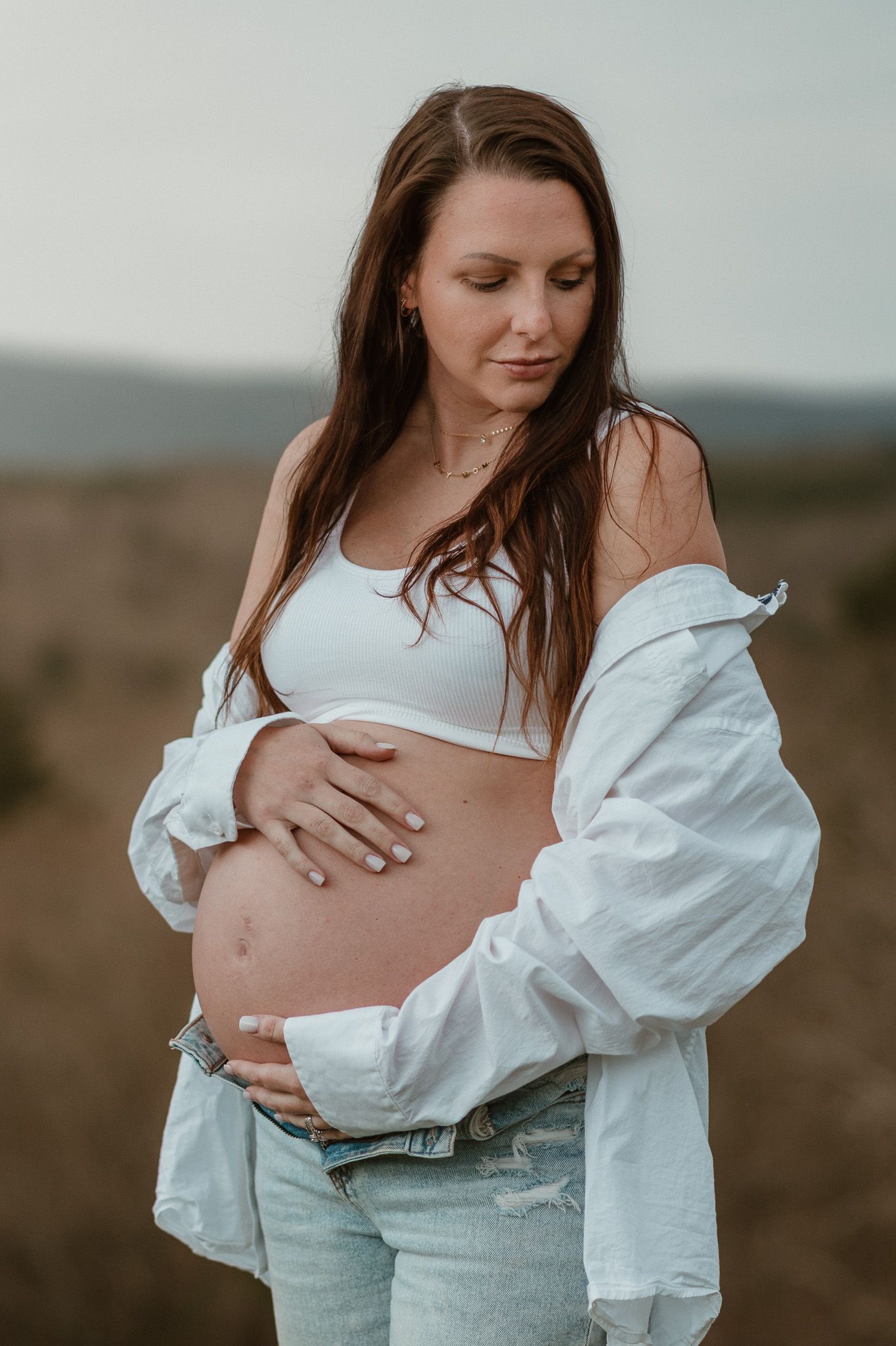 Expecting mom looking off shoulder holding her bump during maternity session on raccoon mountain in chattanooga tn, mountain overlook