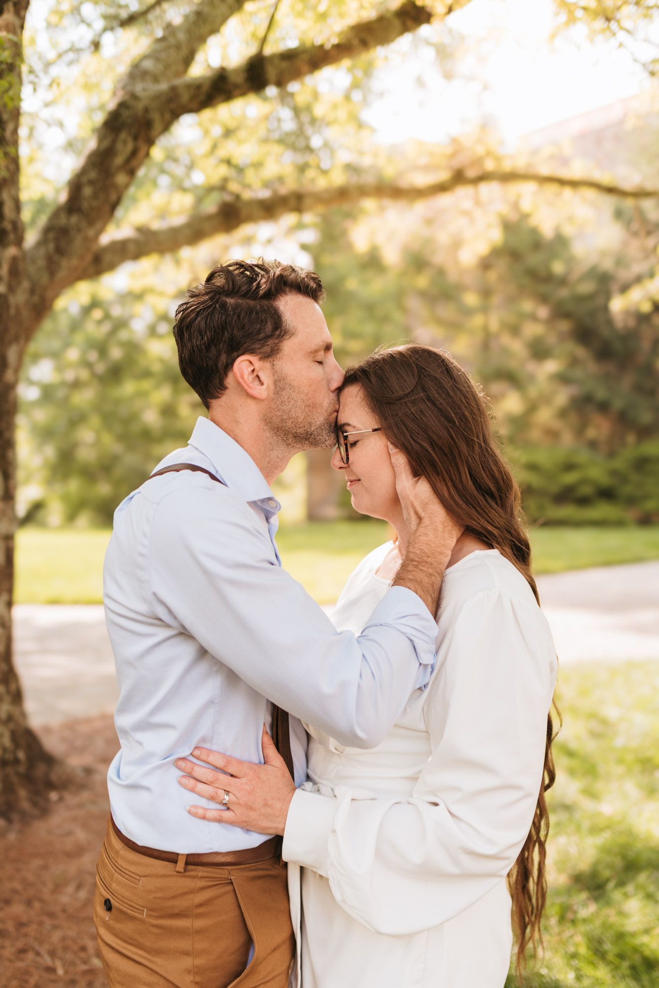 Couple standing close while husband kisses wife's forehead, eyes closed, during outdoor morning session on lookout mountain Georgia