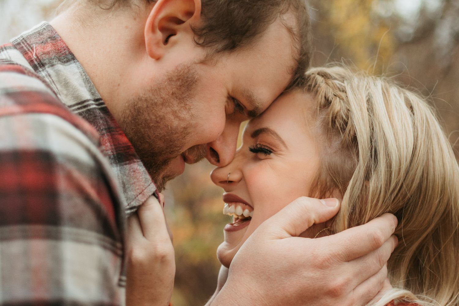 Close up of couple forehead to forehead laughing during outdoor fall couples session