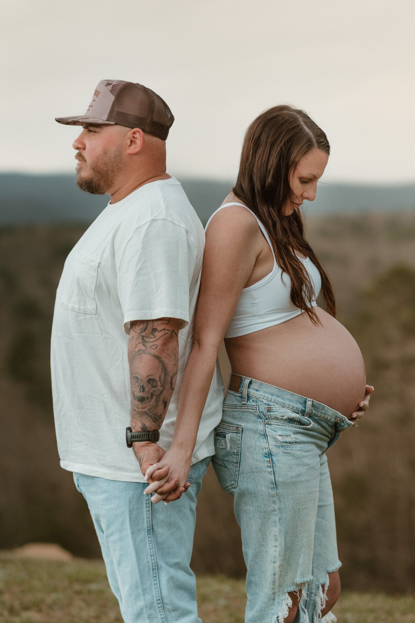 Expecting couple standing back to back looking down and out during maternity session at raccoon mountain chattanooga TN, mountain overlook