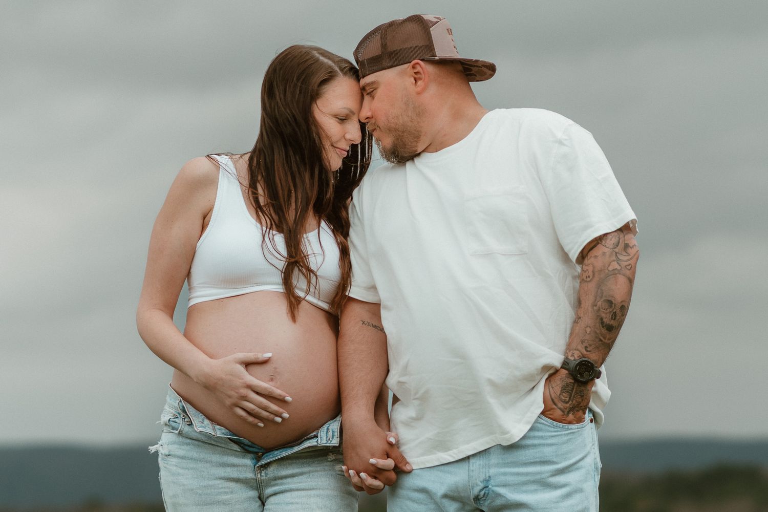 Moody photo of expecting couple standing side by side forehead to forehead eyes closed during maternity session on raccoon mountain TN