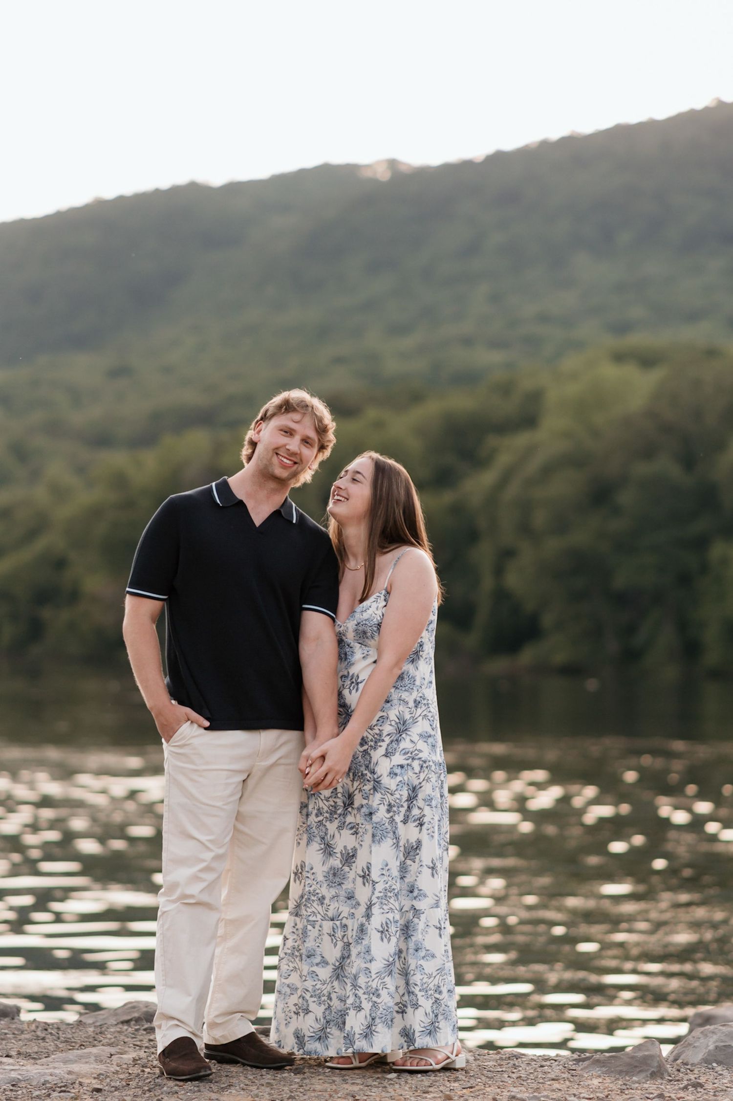 Couple standing close holding hands after surprise proposal near river and raccoon mountain during engagement session
