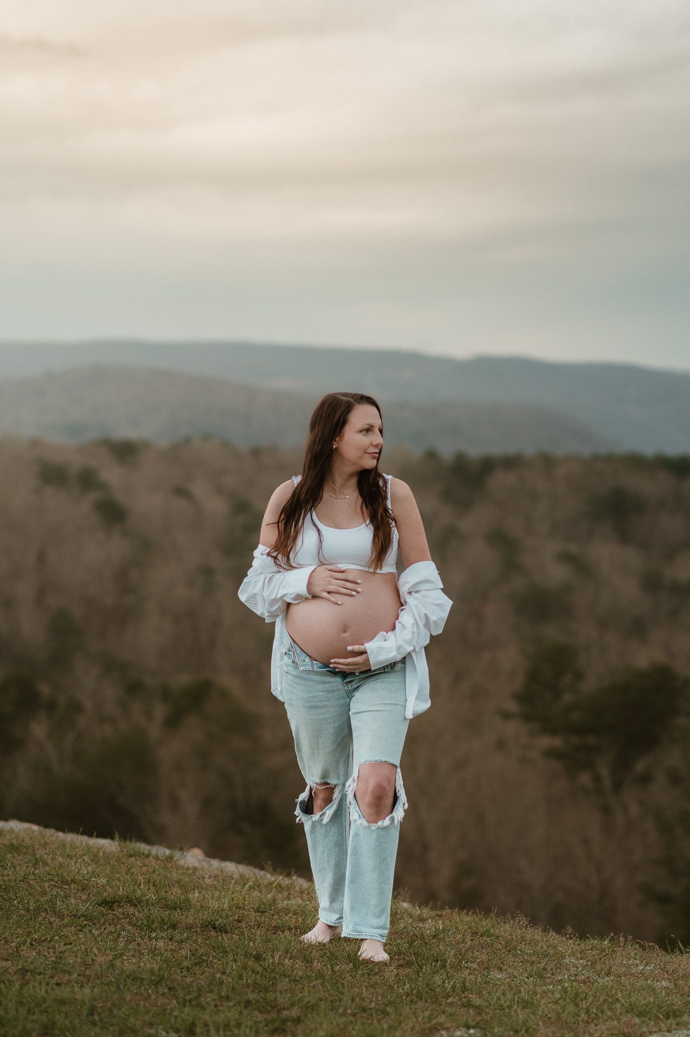Expecting mom looking to side holding her bump during maternity session on raccoon mountain in chattanooga tn, mountain overlook