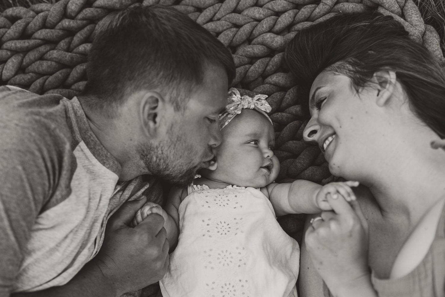 Parents lying close with their baby, sharing a tender moment during a lifestyle family session