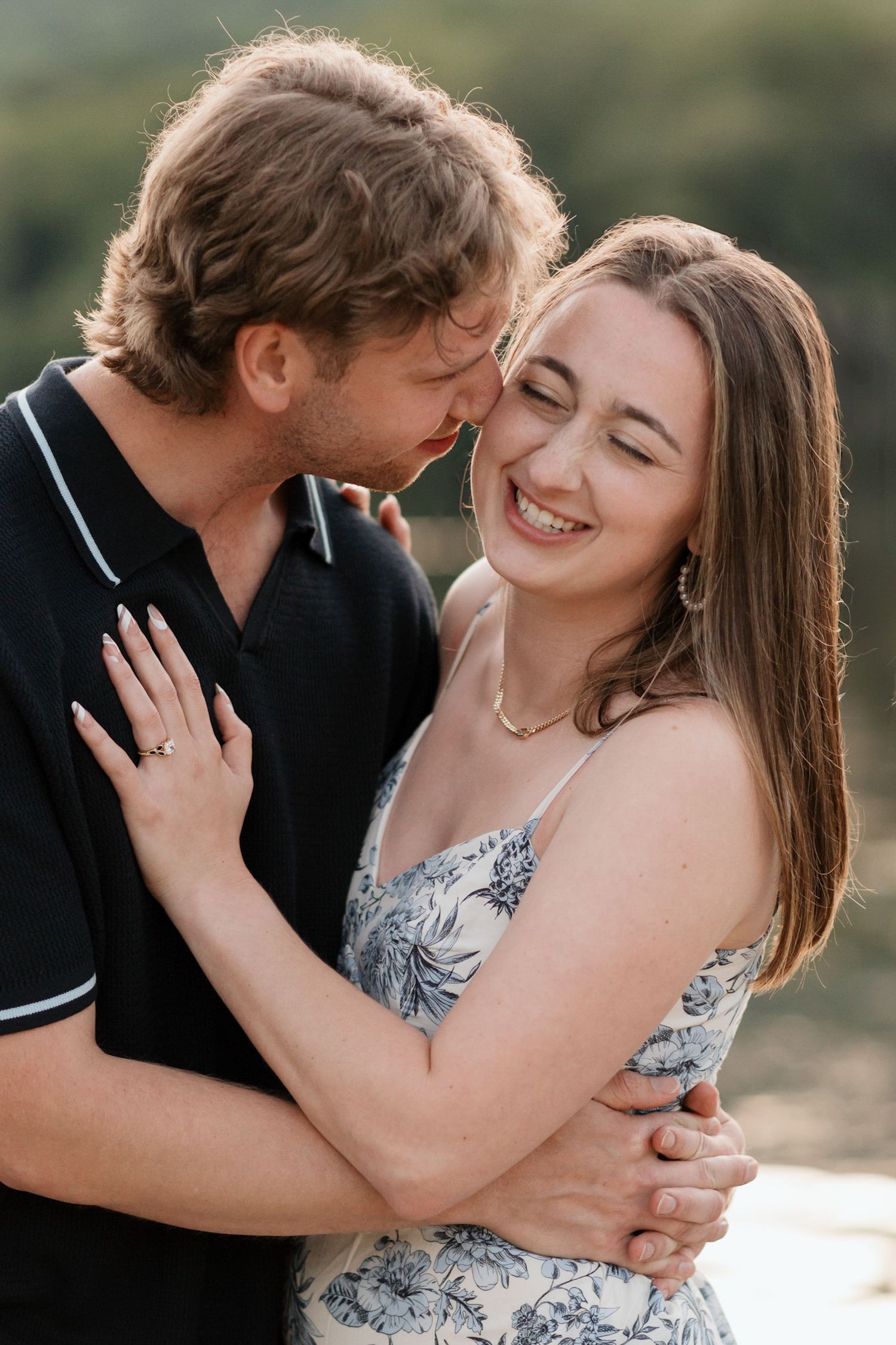 Couple laughing as man holds nose to fiances cheek in proposal engagement session