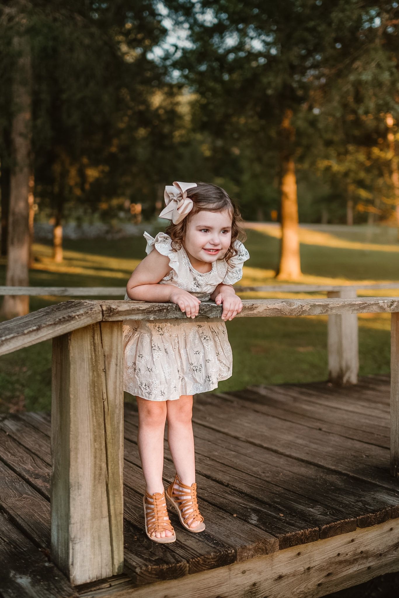 Toddler girl standing on bridge looking out in Hixson, Tennessee, warm golden hour light