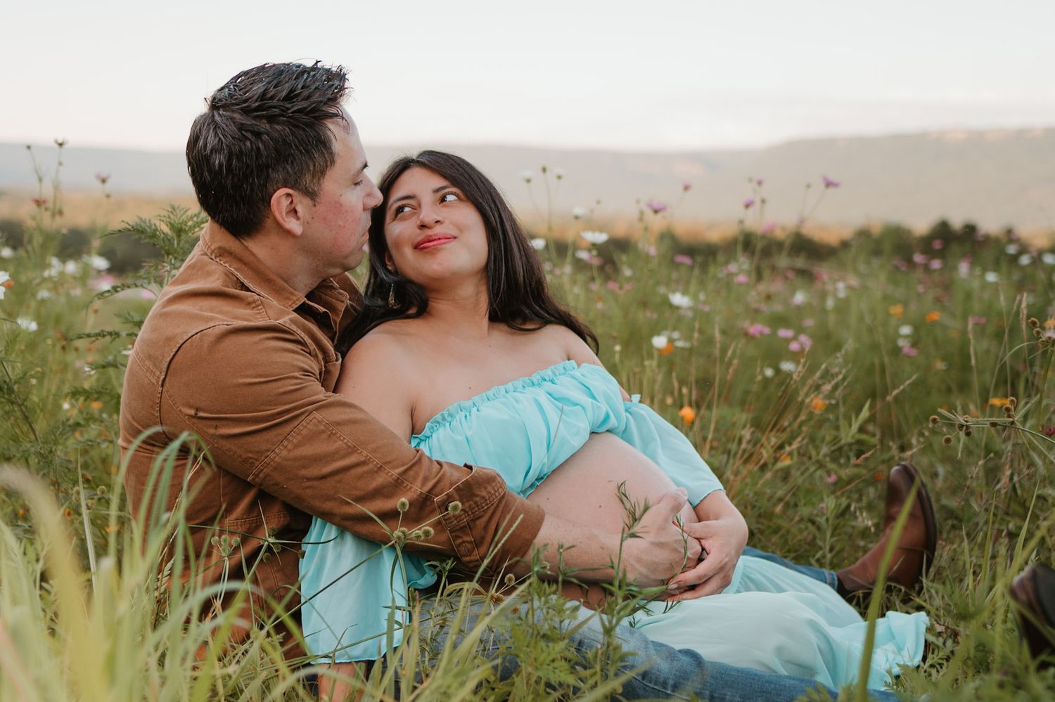 Expecting couple sitting in a wildflower field during golden hour maternity session at Fox Mountain Farm in Rising Fawn, Georgia