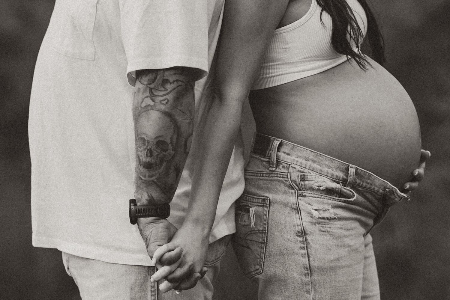 Close-up of expecting couple holding hands with bump visible during a black and white maternity session on Raccoon Mountain in Chattanooga