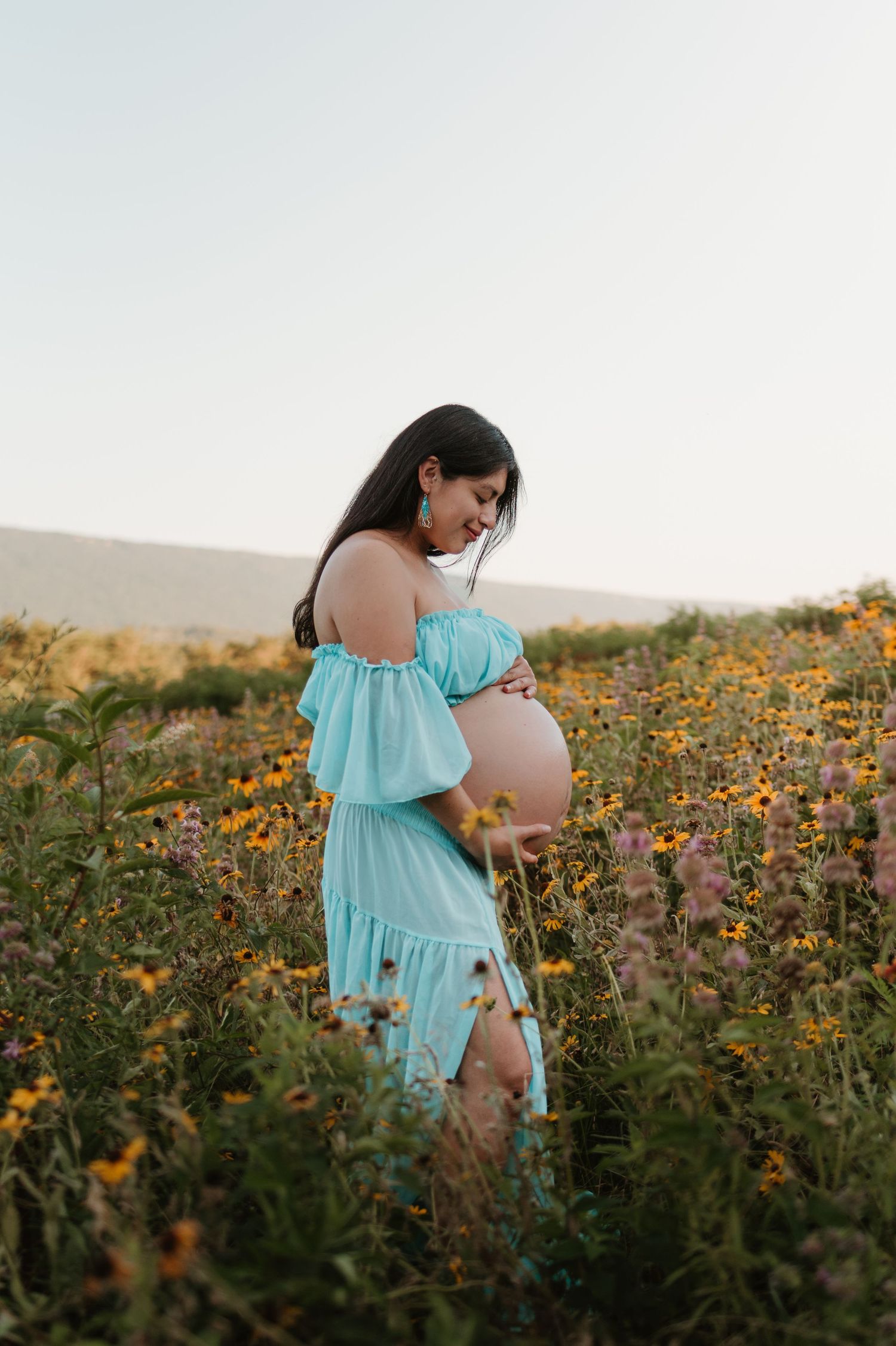 Itzayana looking at belly in a wildflower field at Fox Mountain Farms, Chattanooga, TN – maternity session, soft summer light