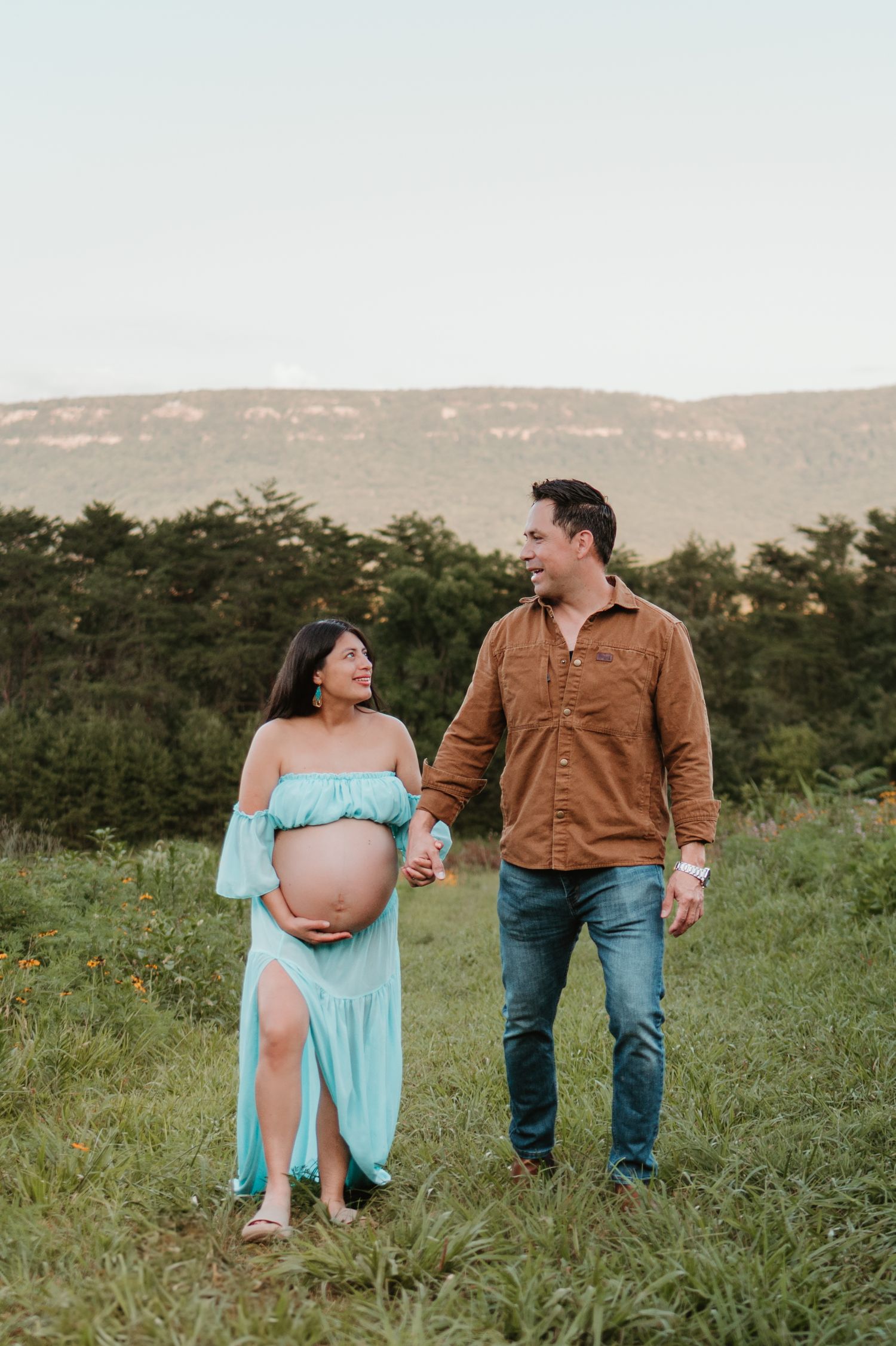 Itzayana and husband walking in a wildflower field at Fox Mountain Farms, Chattanooga, TN – maternity session, soft summer light