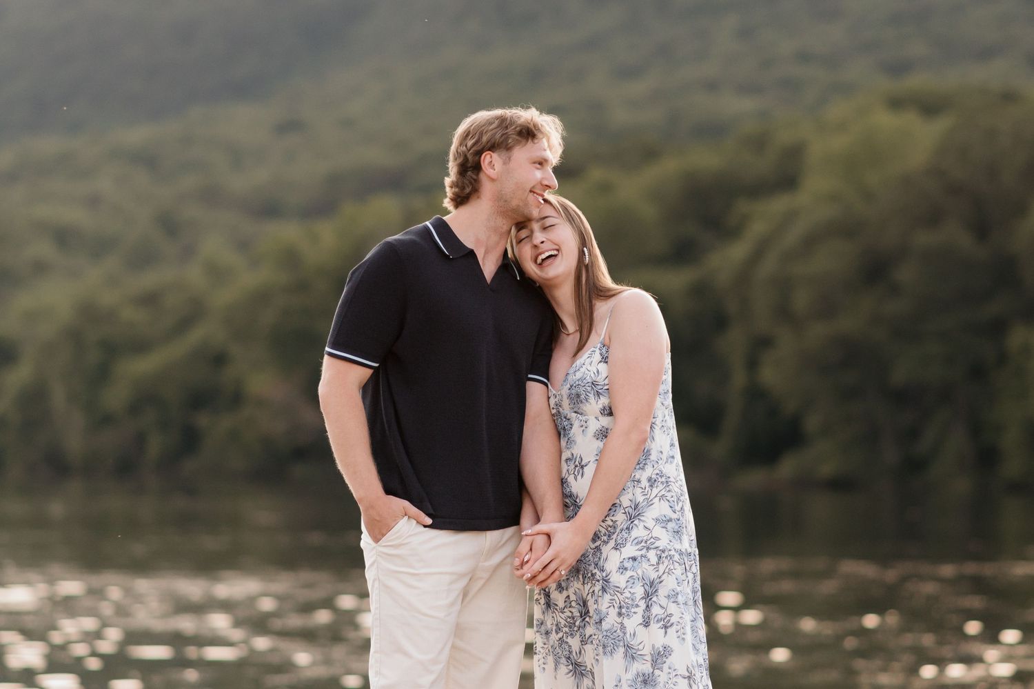 Couple laughing holding hands after surprise proposal near river and raccoon mountain during engagement session