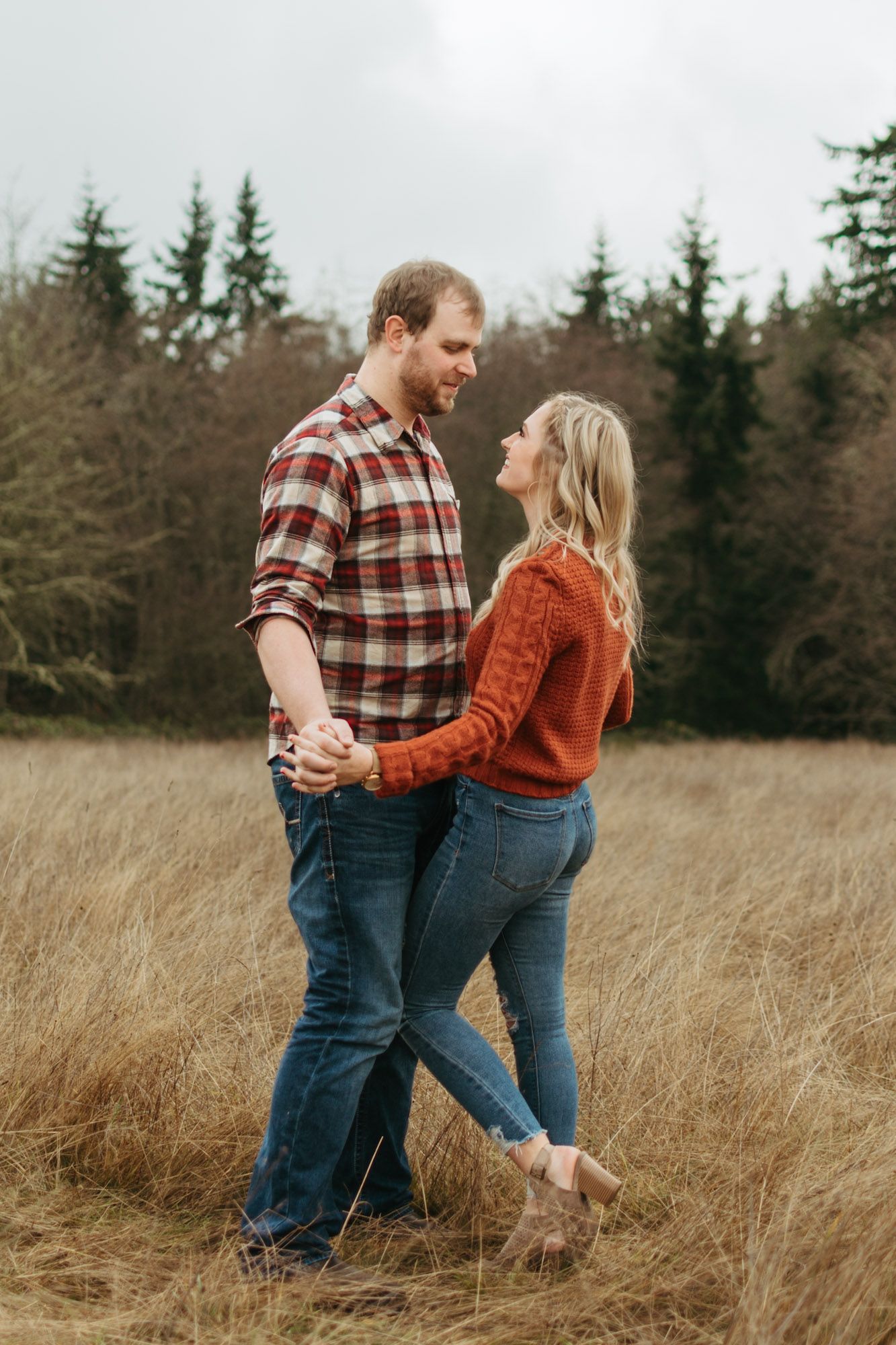 Couple standing close holding hands and looking at each other during outdoor fall couples engagement session