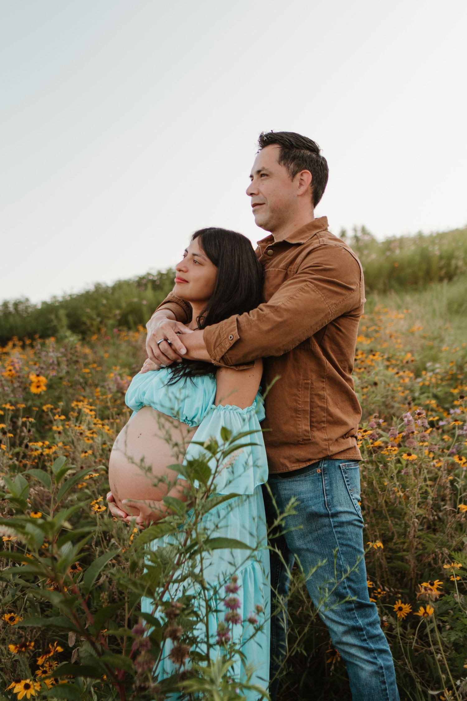 Couple looking out away from camera in a wildflower field at Fox Mountain Farms, Chattanooga, TN – maternity session, soft summer light