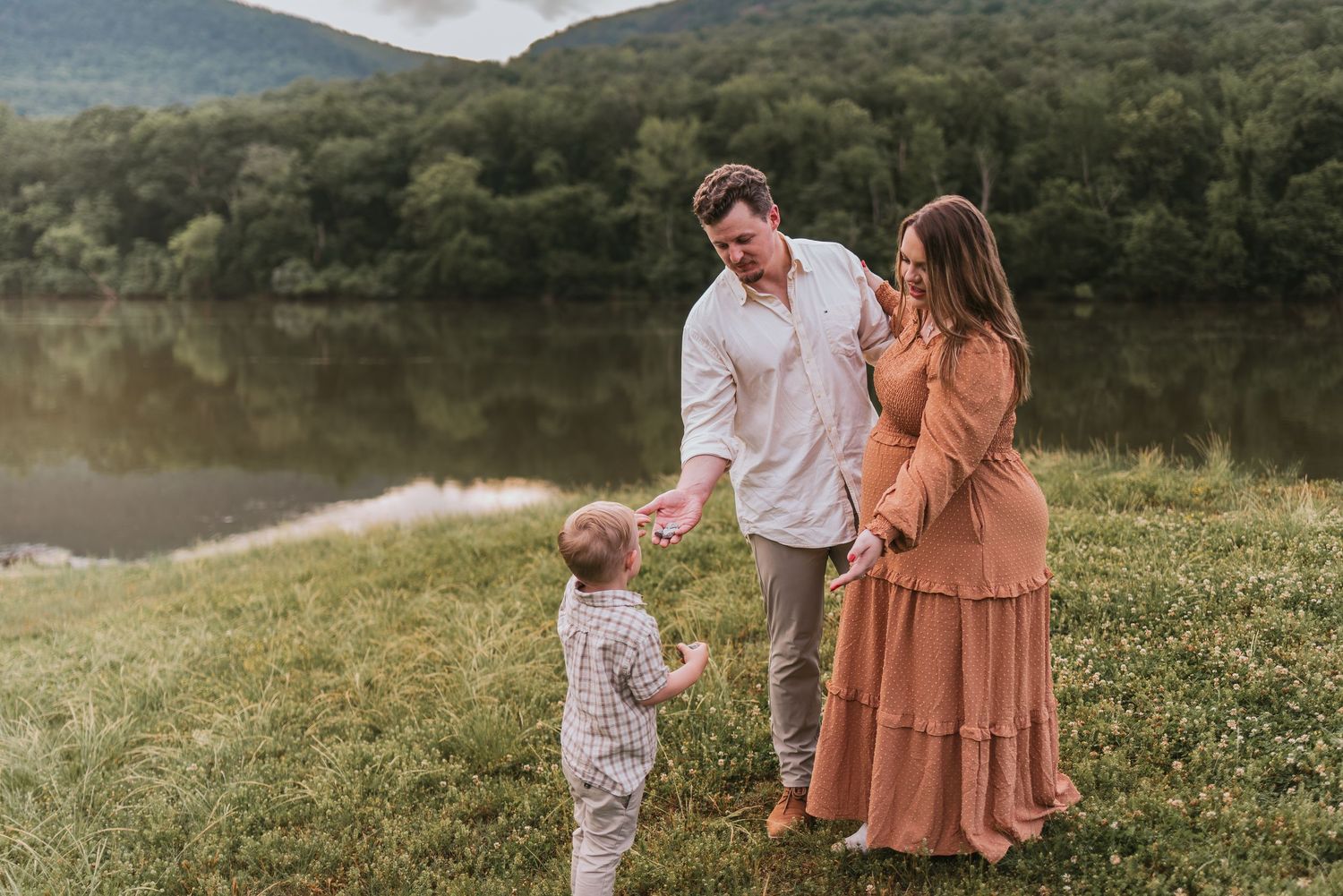 Toddler handing parents flowers in Chattanooga, TN – family maternity session, soft summer light, mountains and water