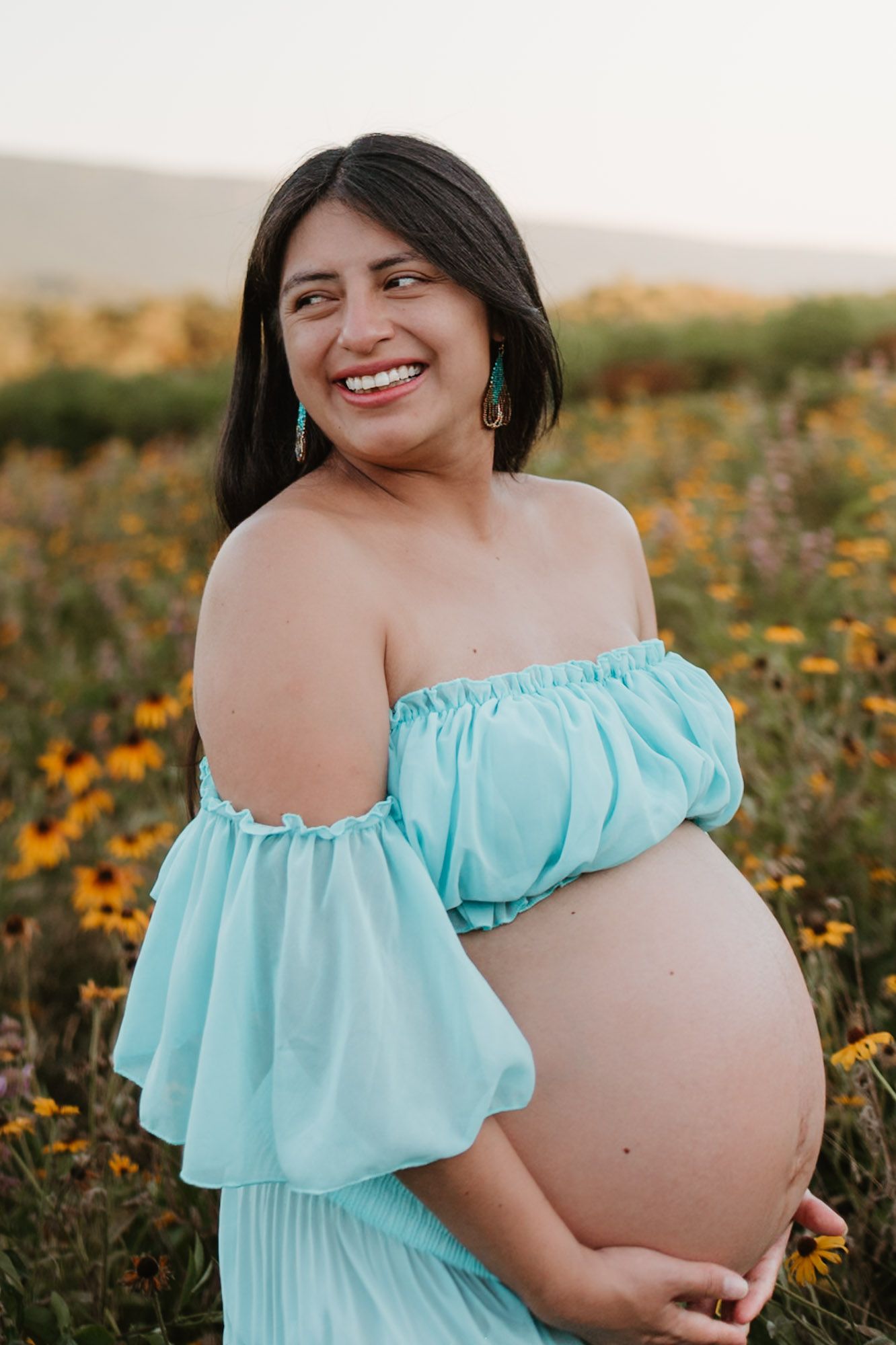 Expecting mom laughing off shoulder in a wildflower field during golden hour maternity session at Fox Mountain Farm in Rising Fawn, Georgia