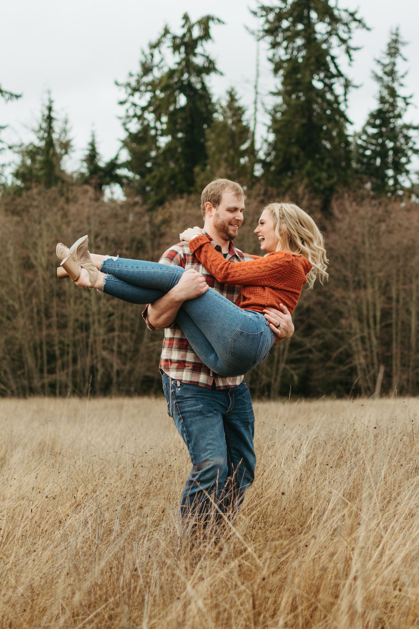 Couple standing in field with man carrying woman and spinning during outdoor fall couples engagement session