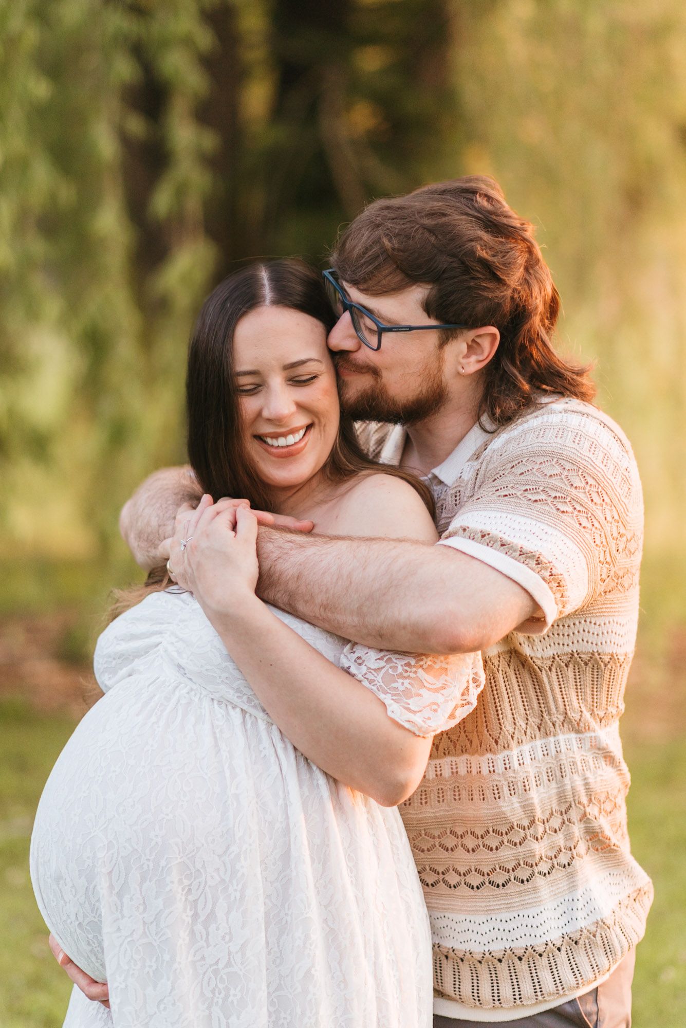 Couple embracing during a golden hour maternity session in Jasper, Tennessee, with husband kissing wife’s cheek