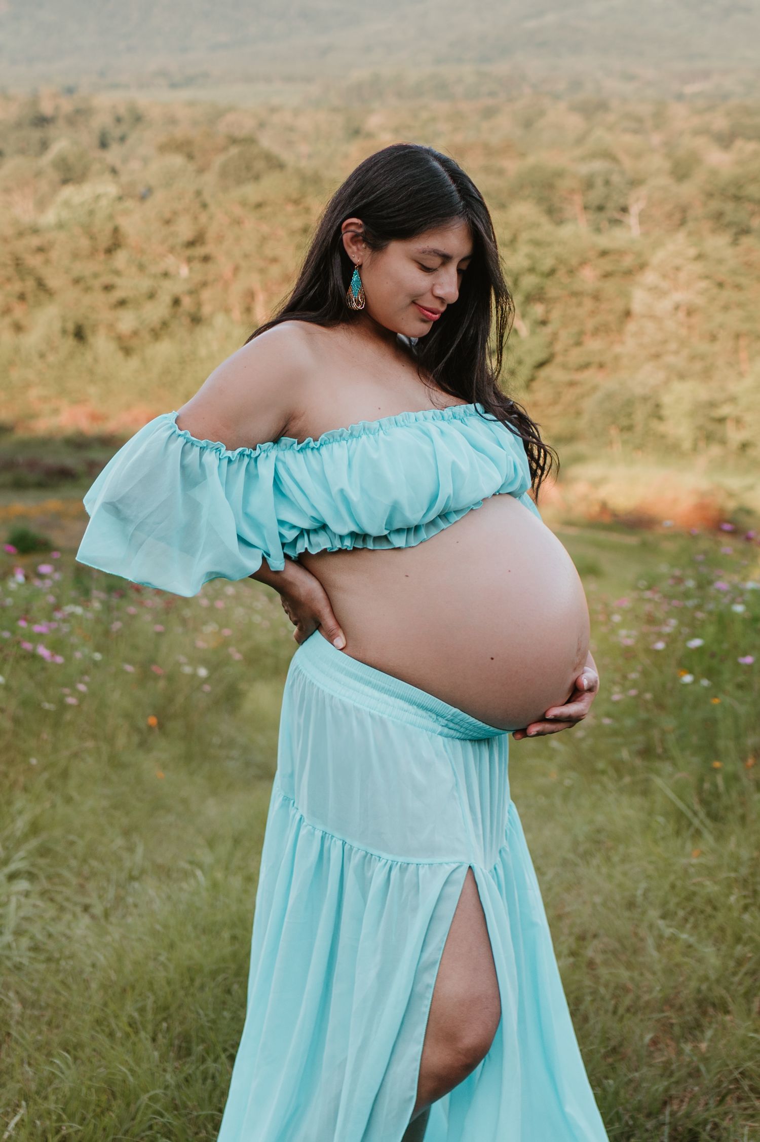 Itzayana looking at belly in a wildflower field at Fox Mountain Farms, Chattanooga, TN – maternity session, soft summer light