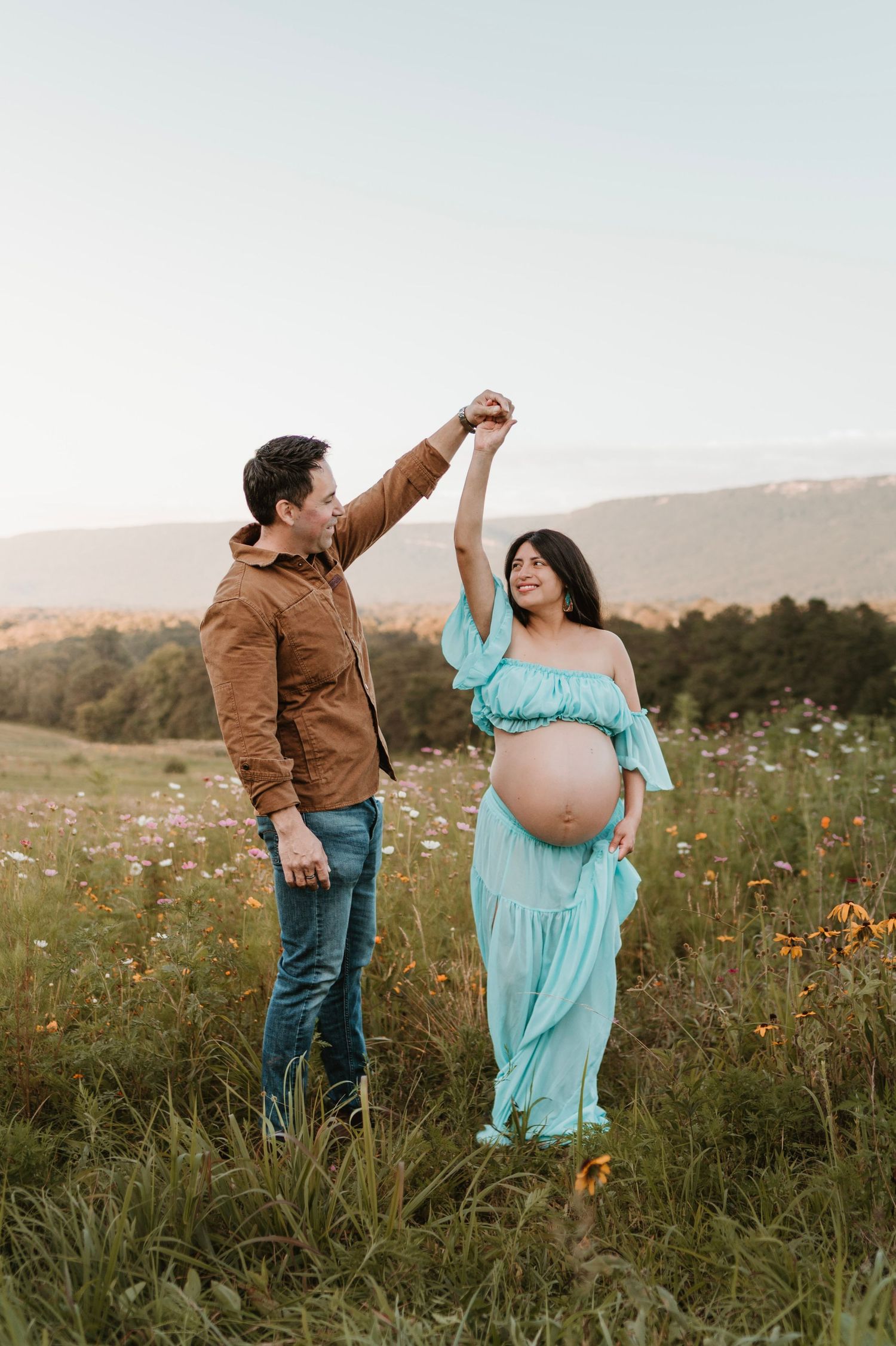 Expecting couple dancing in a wildflower field during golden hour maternity session at Fox Mountain Farm in Rising Fawn, Georgia