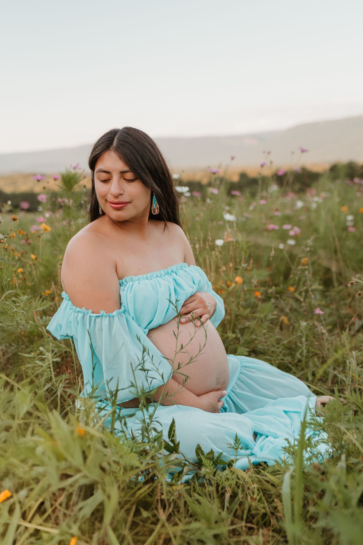 Itzayana sitting in a wildflower field at Fox Mountain Farms, Chattanooga, TN – maternity session, soft summer light