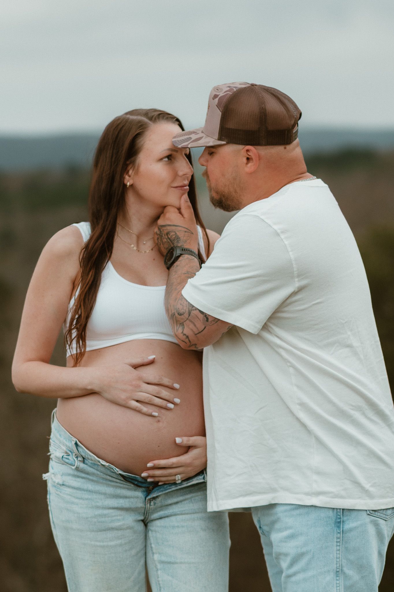 Man holding expecting moms chin looking in her eyes during maternity session at raccoon mountain chattanooga TN, mountain overlook