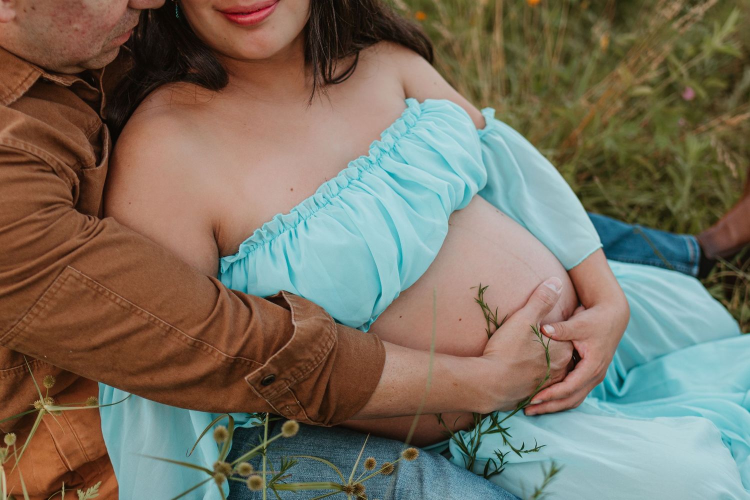 Couple sitting in a wildflower field at Fox Mountain Farms, Chattanooga, TN – maternity session, soft summer light