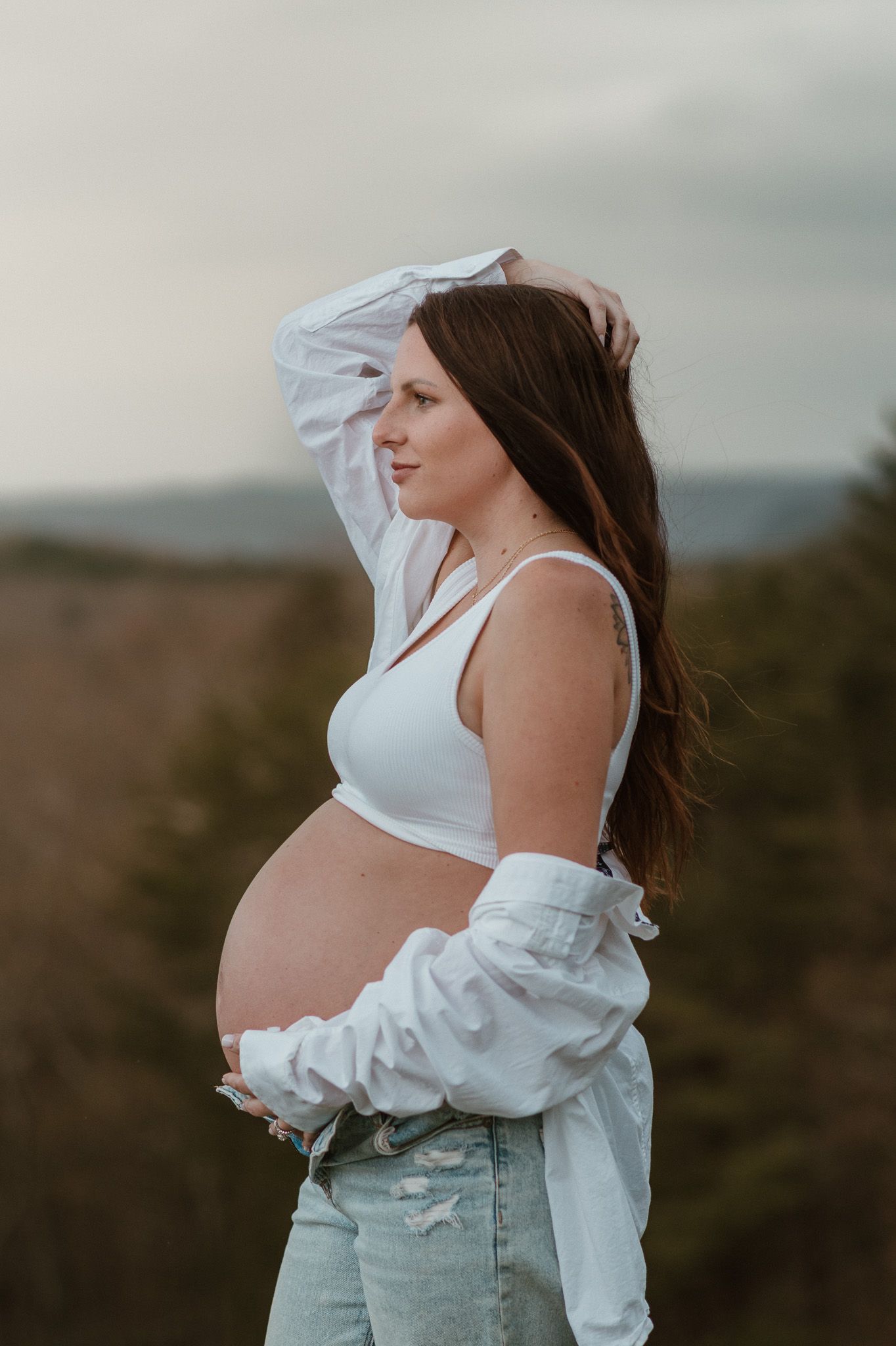 Profile portrait of expecting mom holding bump and playing with hair during maternity session on raccoon mountain chattanooga tn, overlook