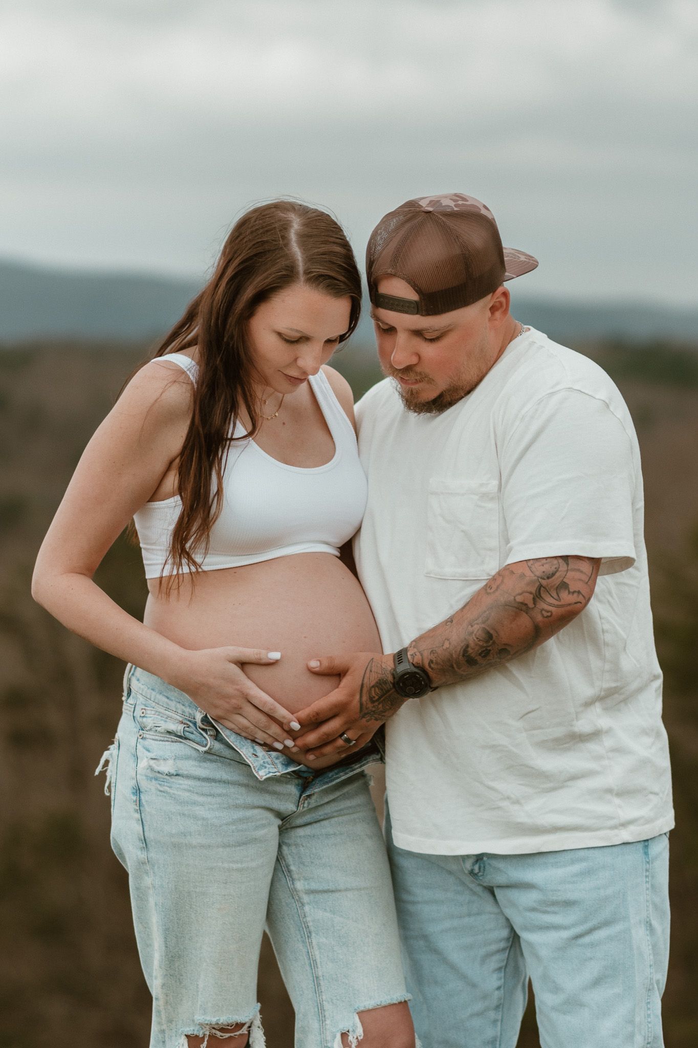 Expecting couple holding and looking at baby bump during maternity session at raccoon mountain chattanooga TN, mountain overlook